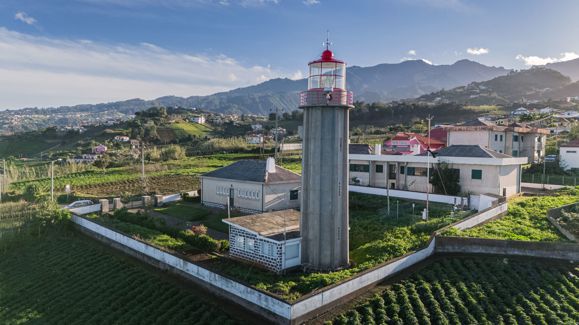 Leuchtturm neben Häusern und kultivierten Feldern auf Madeira.