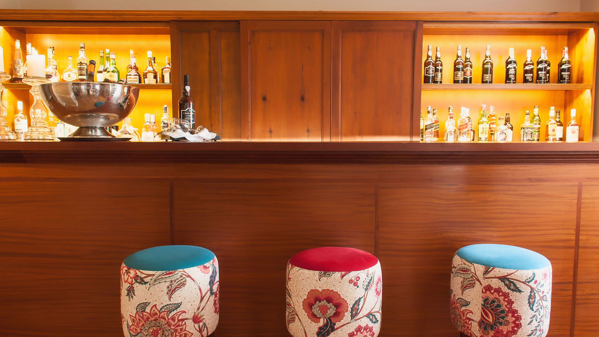Counter with drinks and three small stools.