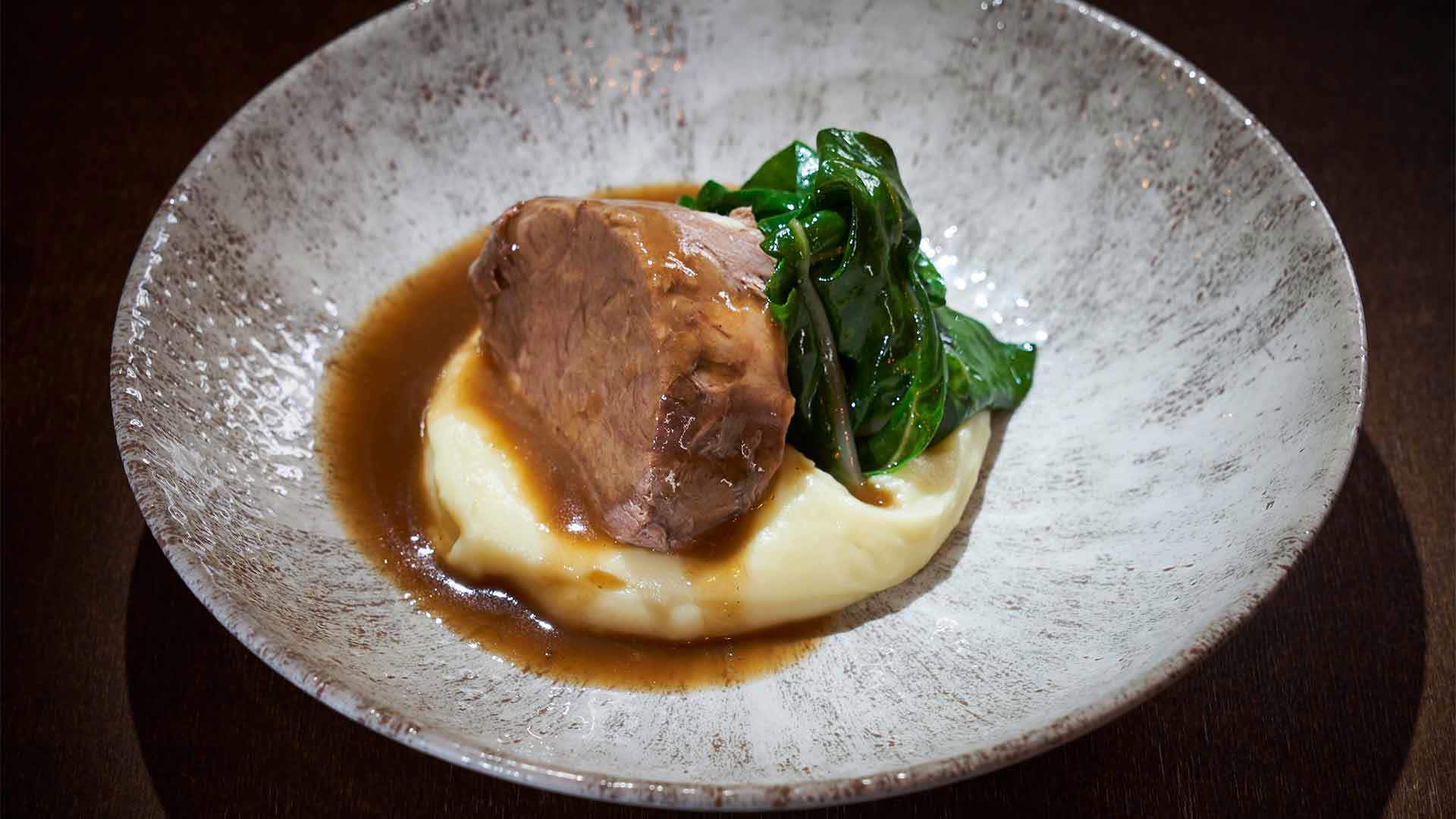 Teller mit Kartoffelpüree, Steak darauf und Kohl.