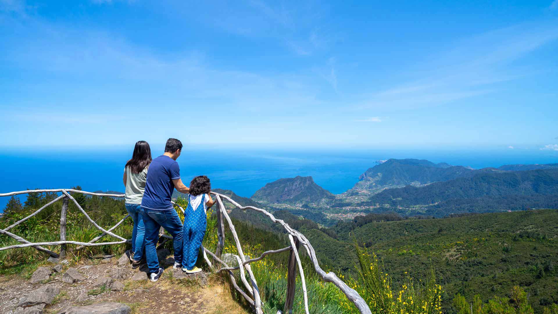 Famille sur un belvédère à Madère avec vue sur montagnes et mer.