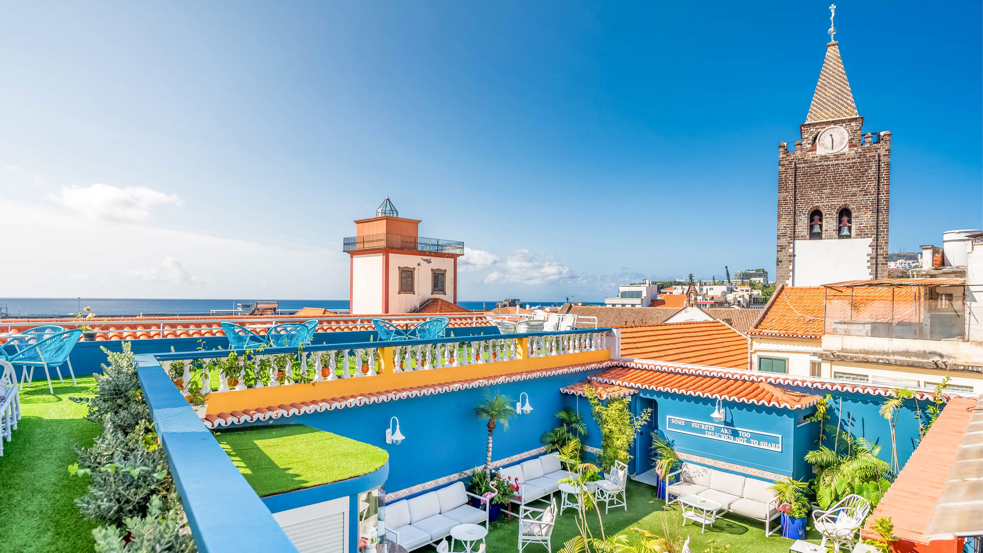 Terrace with blue balcony and church tower in the background.