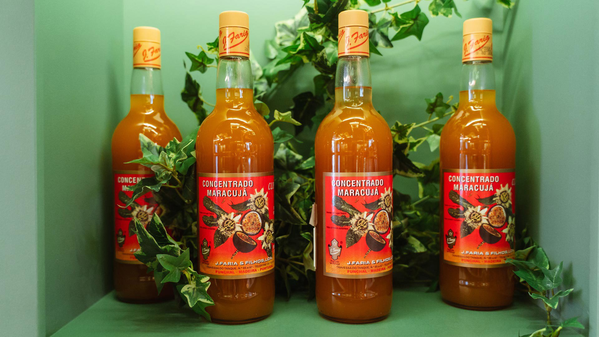 Quatre bouteilles de concentré de fruit de la passion exposées sur un présentoir.