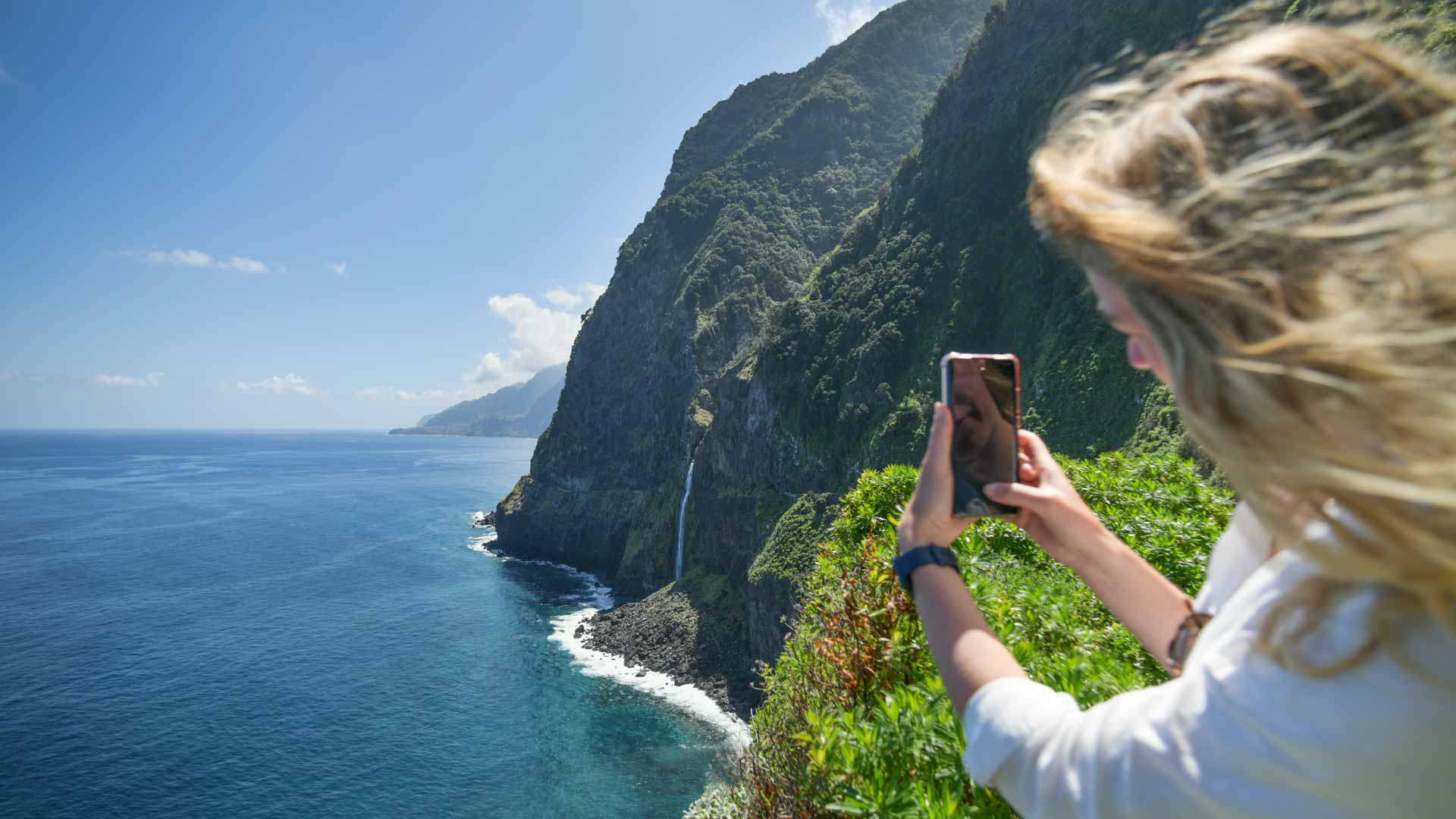 Femme prenant une photo au belvédère avec cascade dans le paysage de Madère.