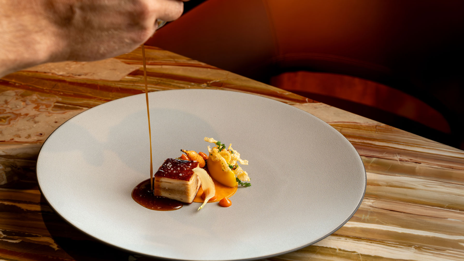 Hand beim Anrichten eines Gerichts im Stil der zeitgenössischen Küch