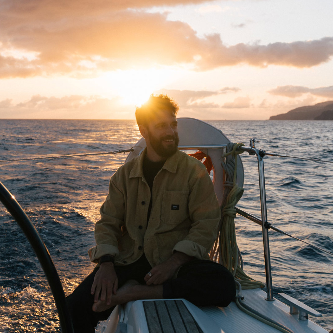Homem num barco ao pôr do sol.