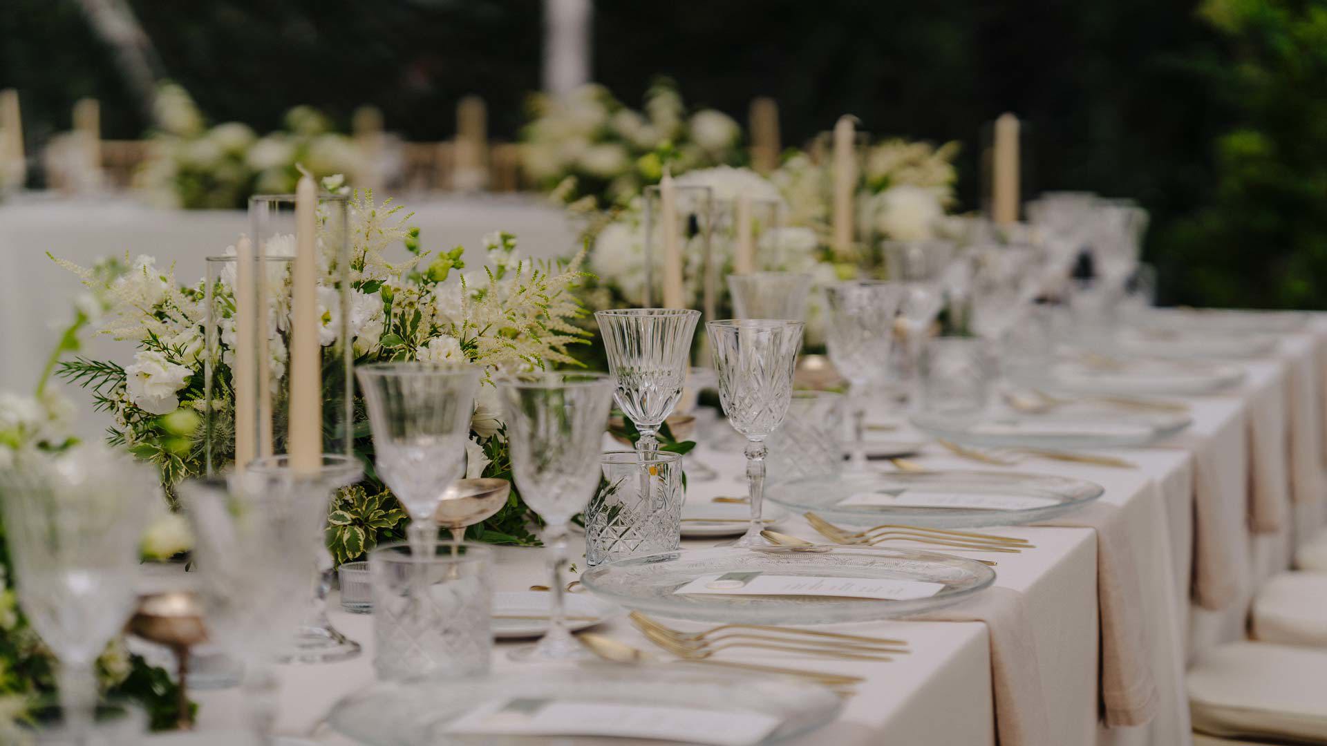 Hochzeitstisch dekoriert mit Blumen, Kerzen und eleganten Gläsern.