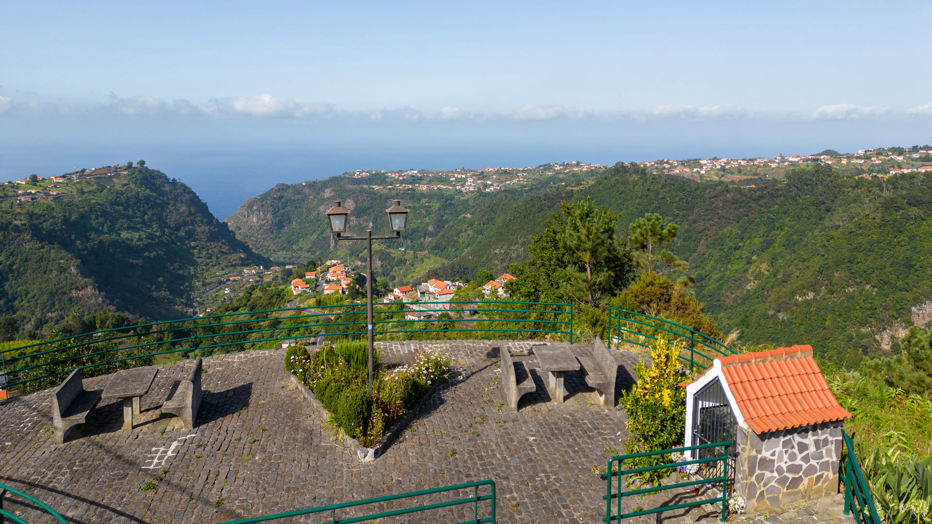 Picknicktische mit Bergblick und Steinhaus auf Madeira.