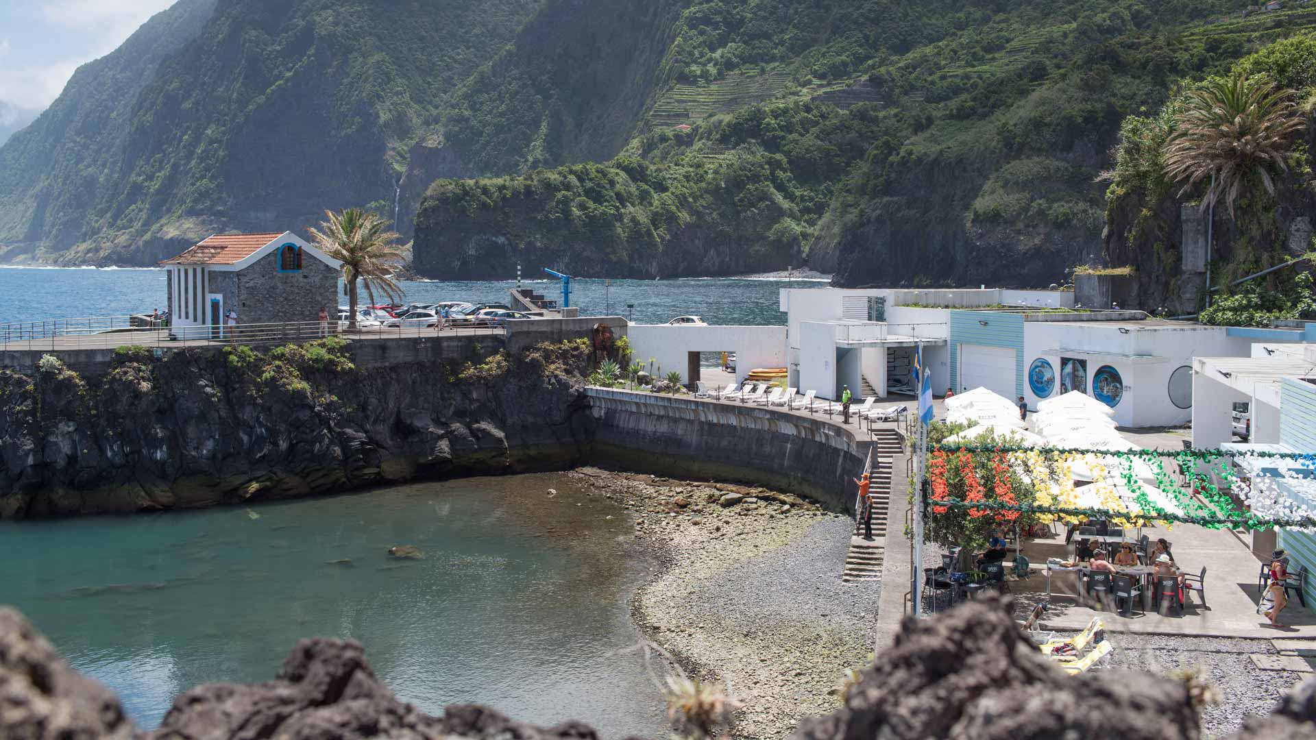 Piscina natural numa baía com esplanada e paisagem de fundo na Madeira.