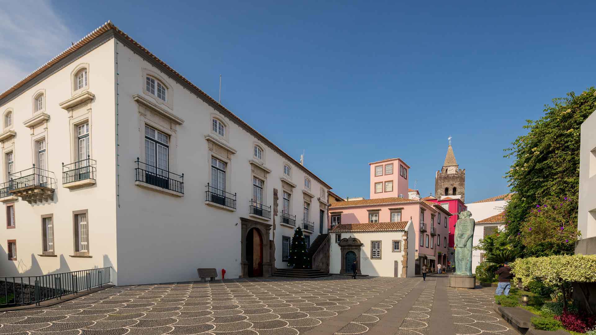 White building in the square with church visible in the background.