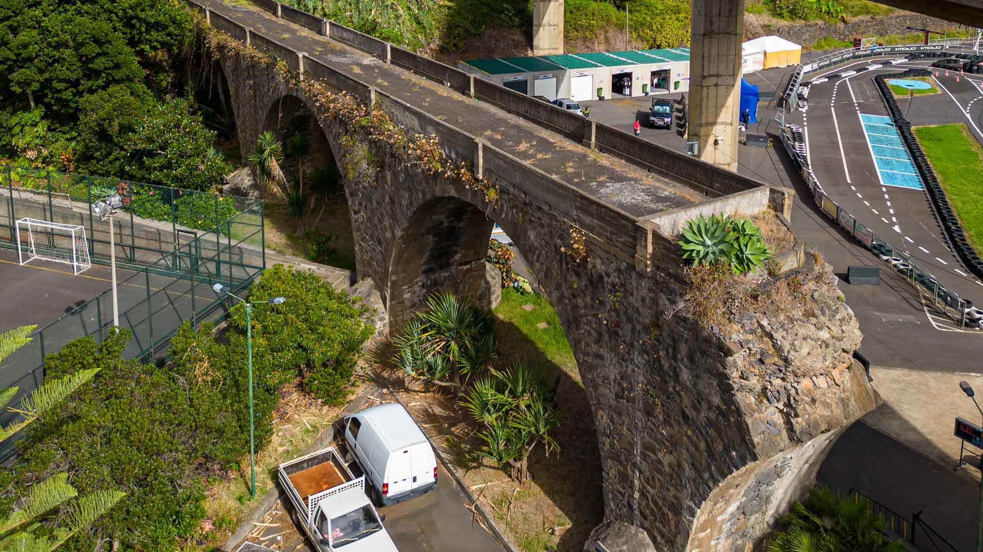 Puente de piedra junto a carretera con vegetación.