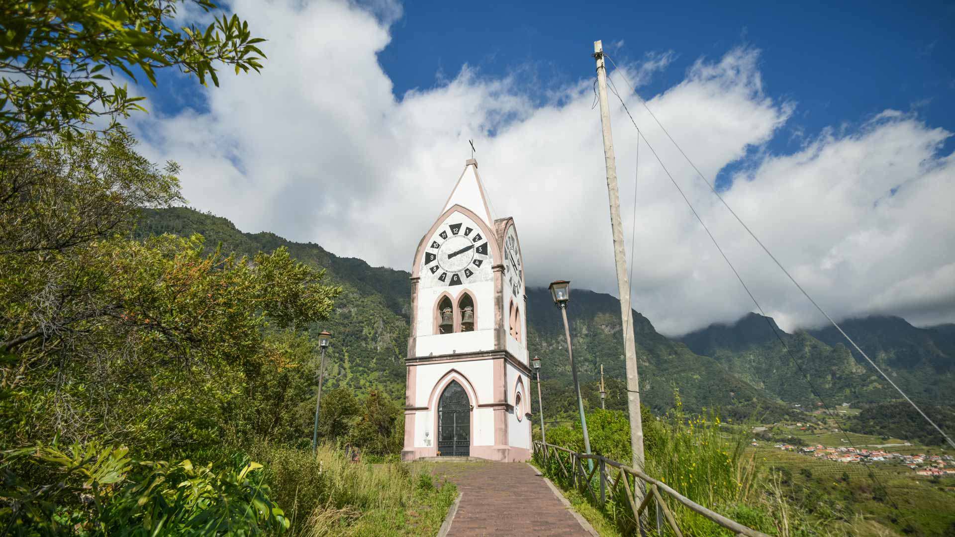 Iglesia con montaña al fondo bajo cielo nublado.