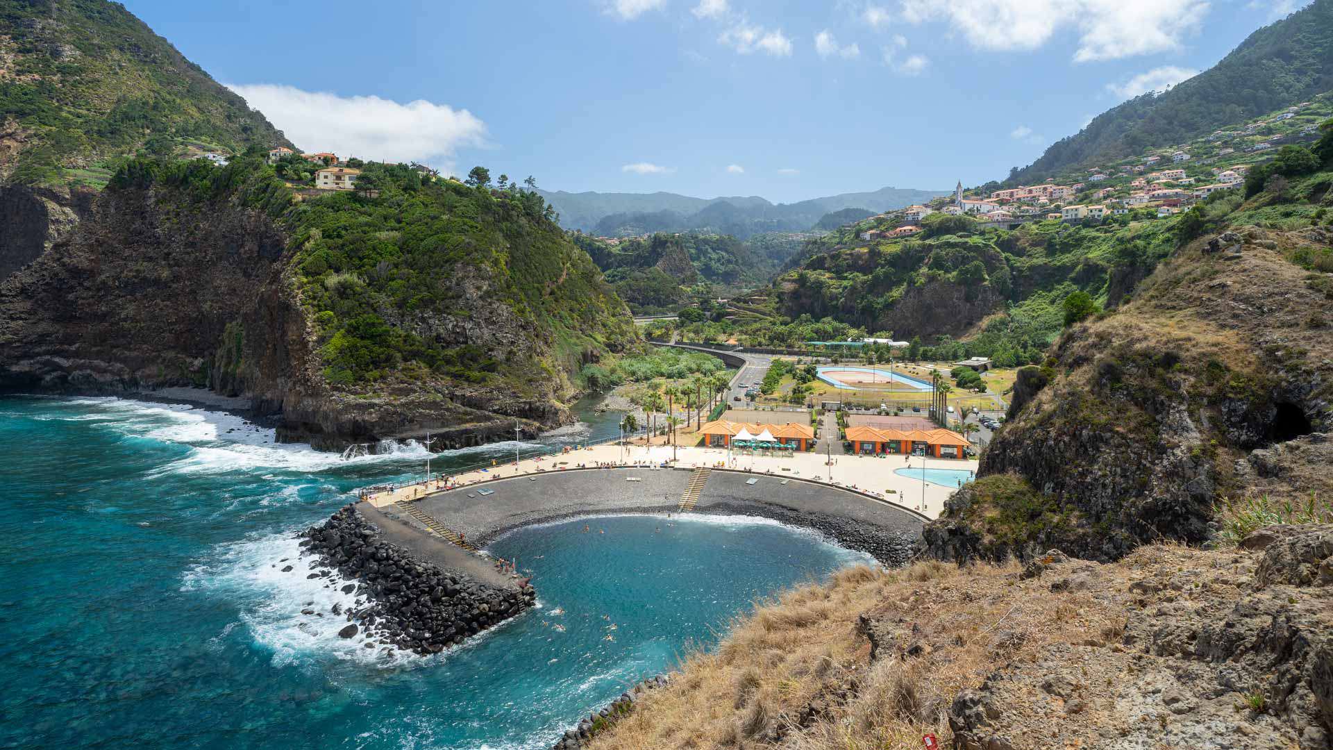 Playa de callao con olas, montañas y casas al fondo en Madeira.