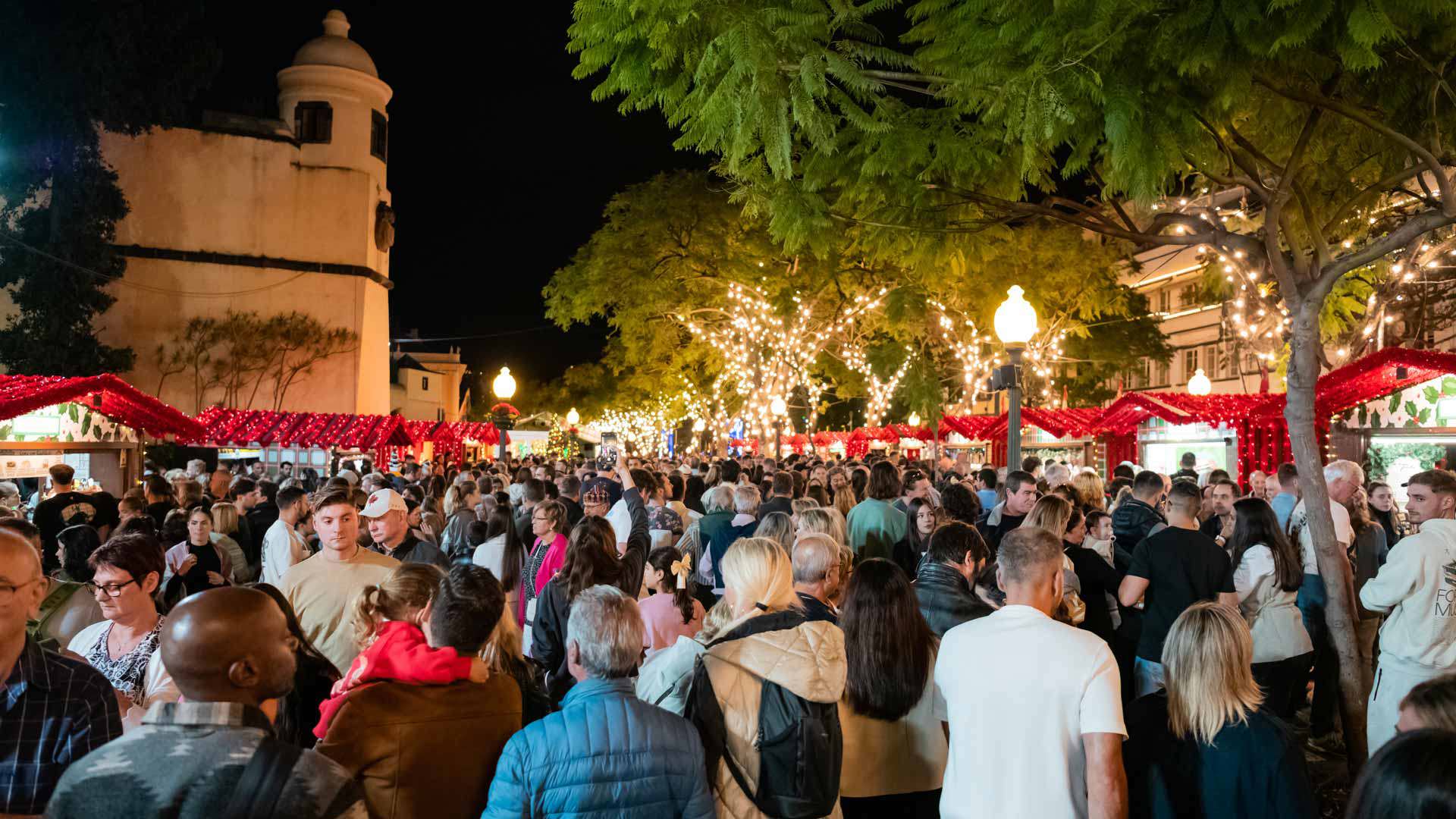Personas junto a los puestos de Navidad con luces en la plaza central de Funchal.