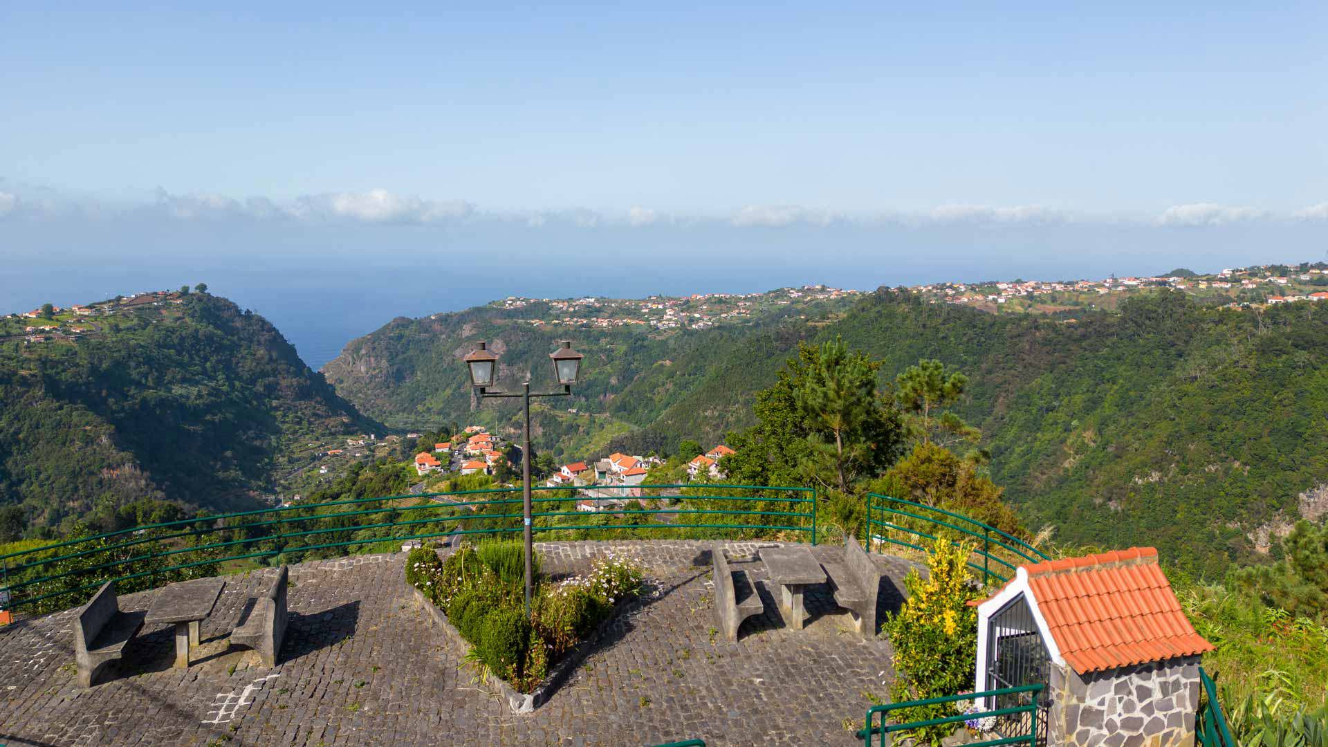 Picknicktische mit Bergblick und Steinhaus auf Madeira.