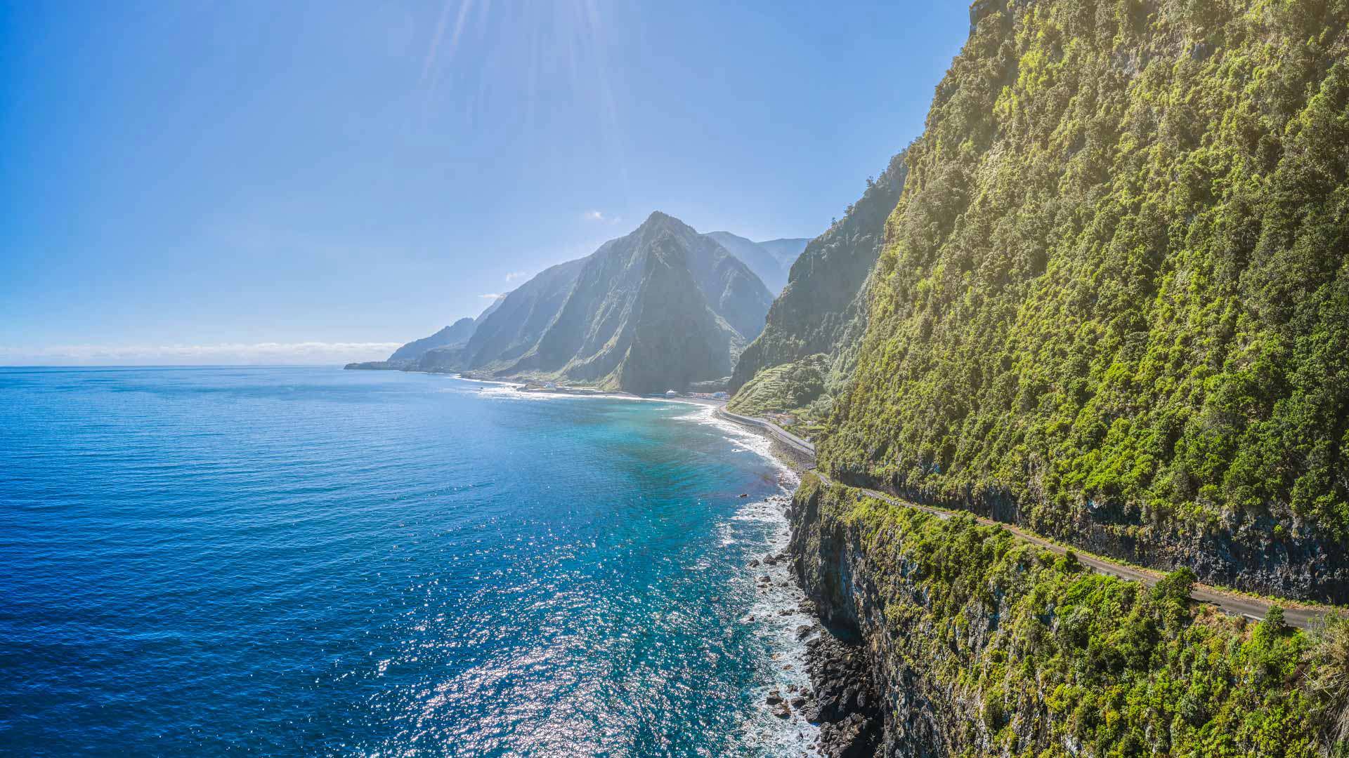 Trail on green mountain with sea view and sun in Madeira.