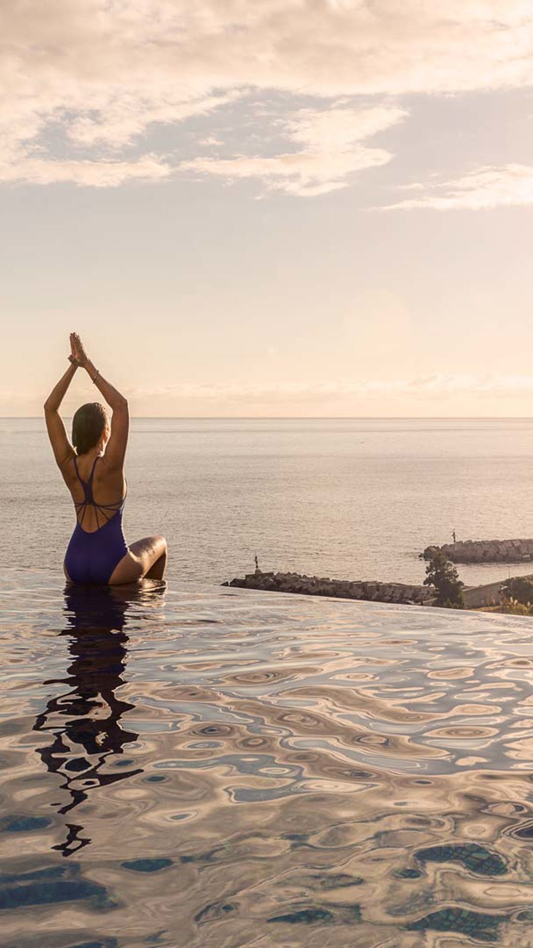 Woman on the poolside practicing yoga in the sun.