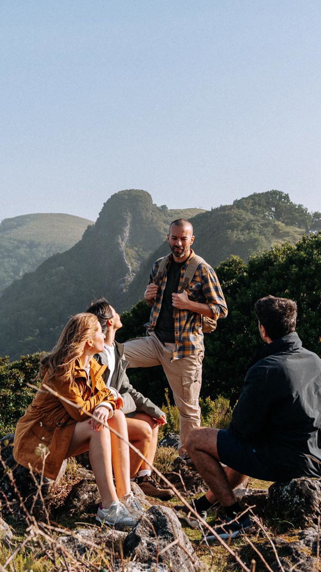 Four people in the mountains under a clear blue sky.