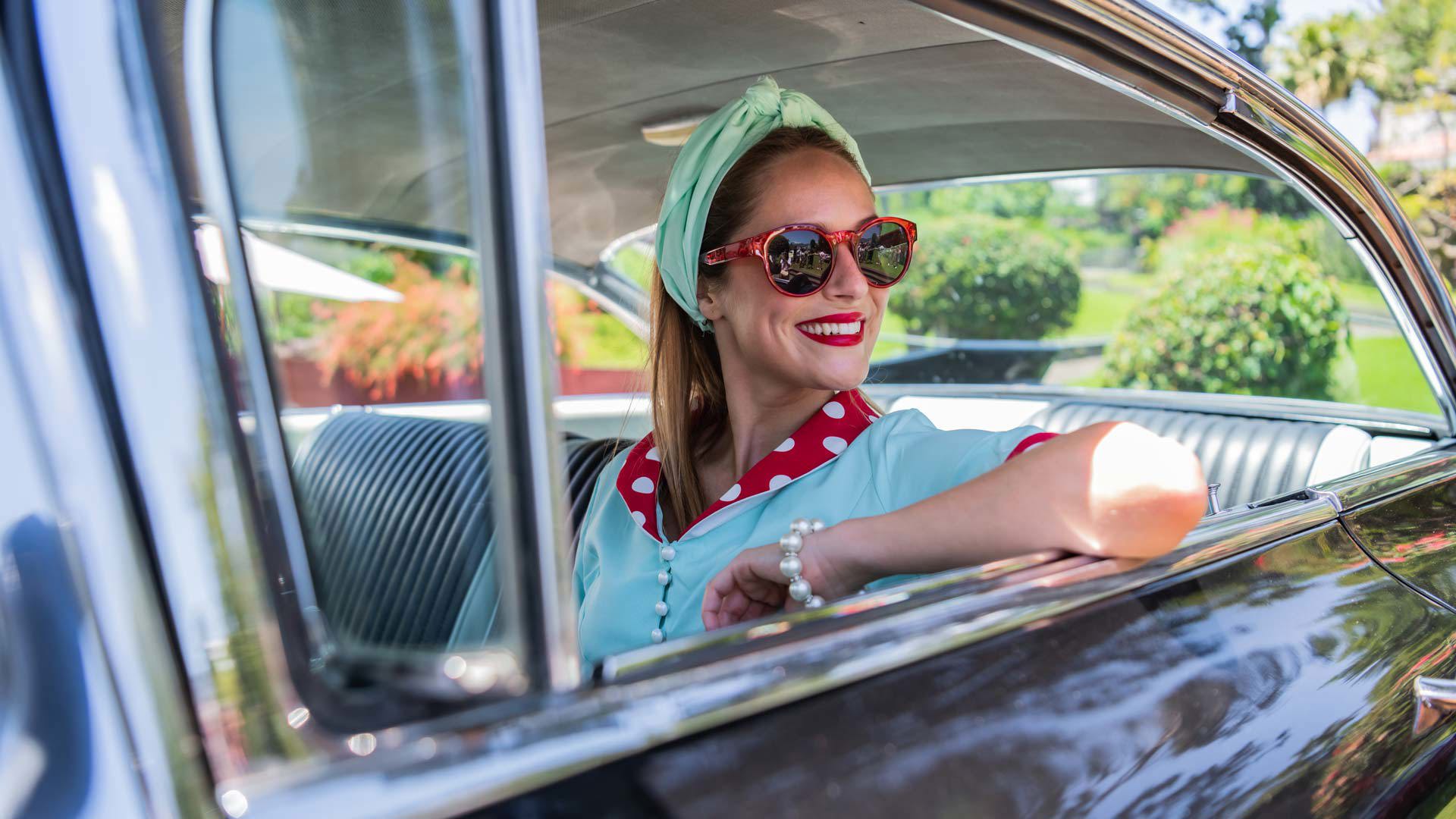 Mujer sentada en el interior de un coche clásico.