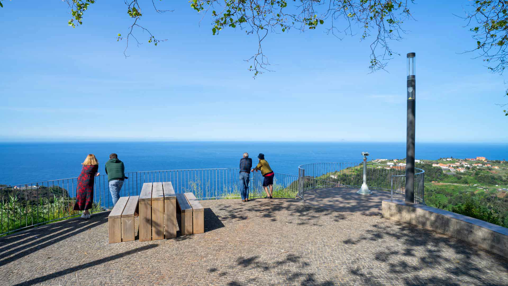 Wooden benches at viewpoint with people in Madeira.