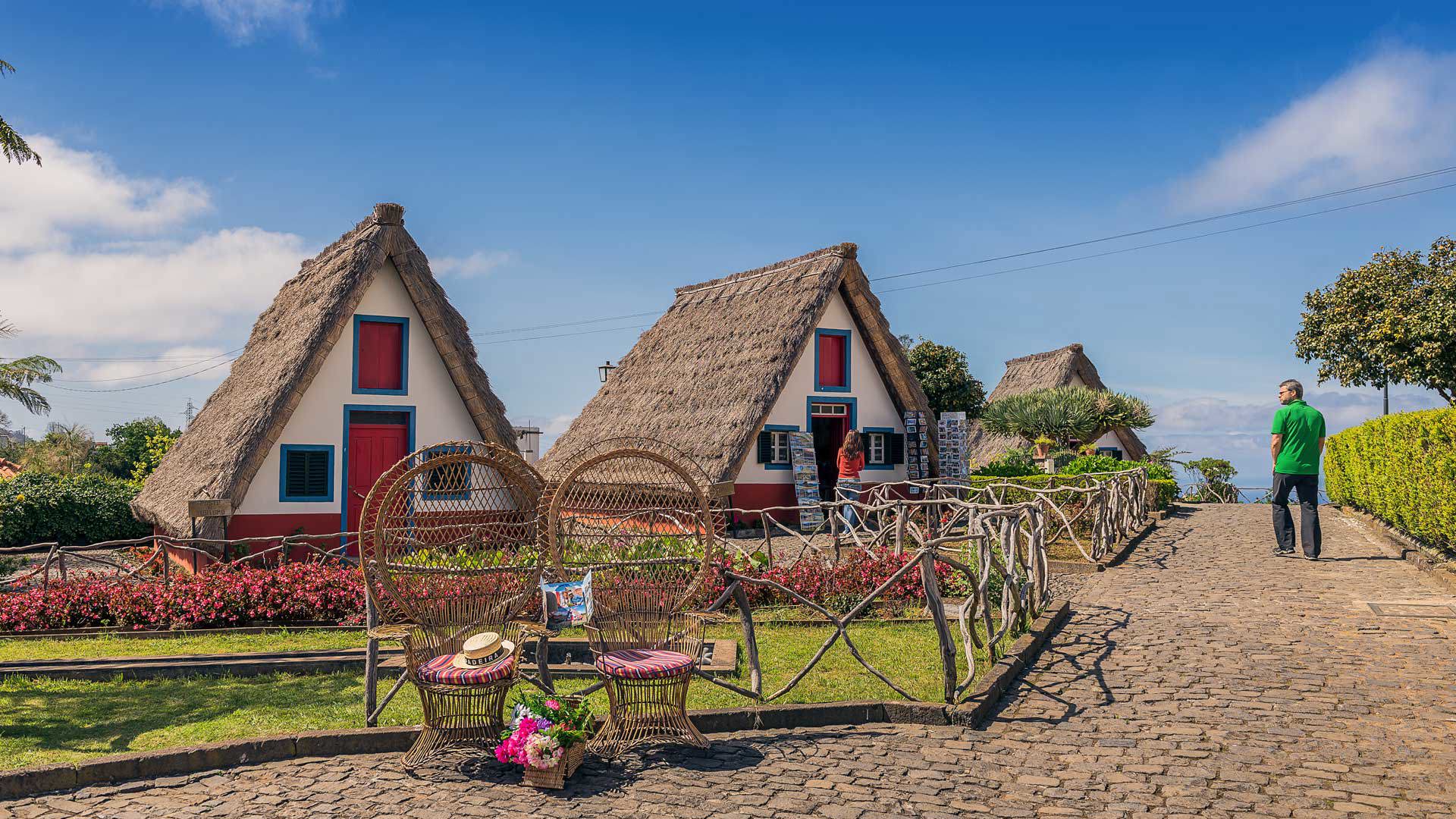 Mann mit grünem Hemd bei dreieckigem Haus mit Strohdach.