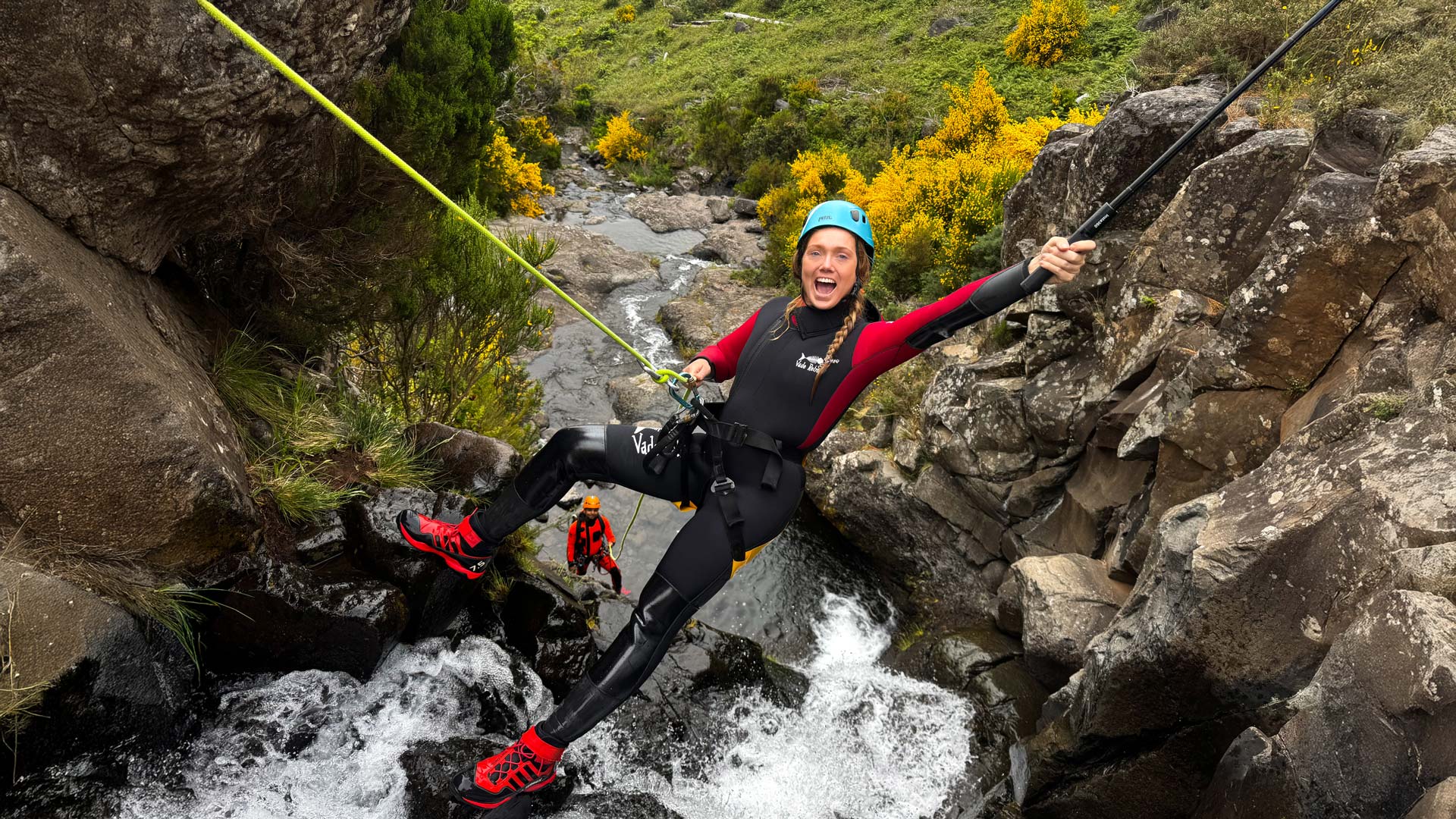 Zwei Frauen beim Canyoning, ausgerüstet, an einem Wasserfall.