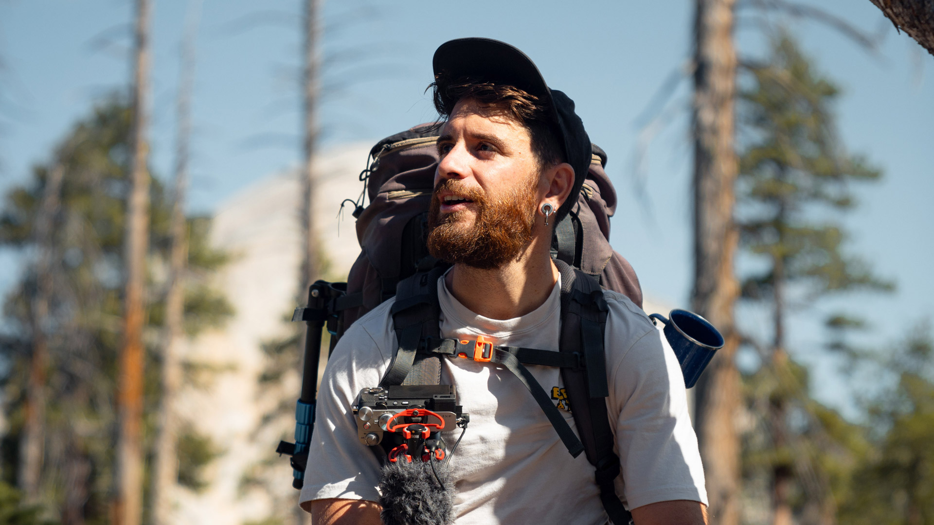 Homem com boné e mochila a sorrir.