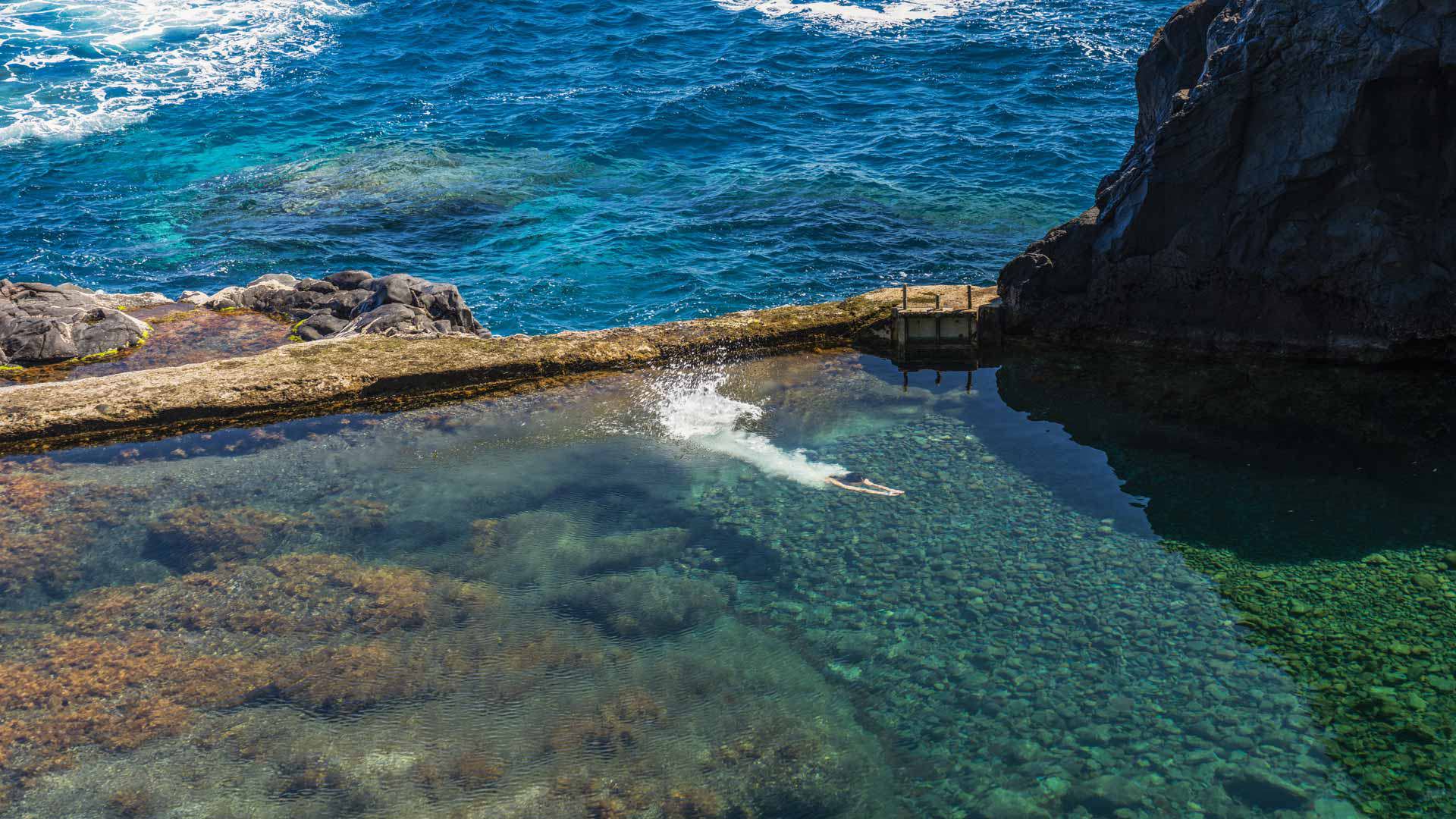 Person swimming in a natural pool by the sea in Madeira.
