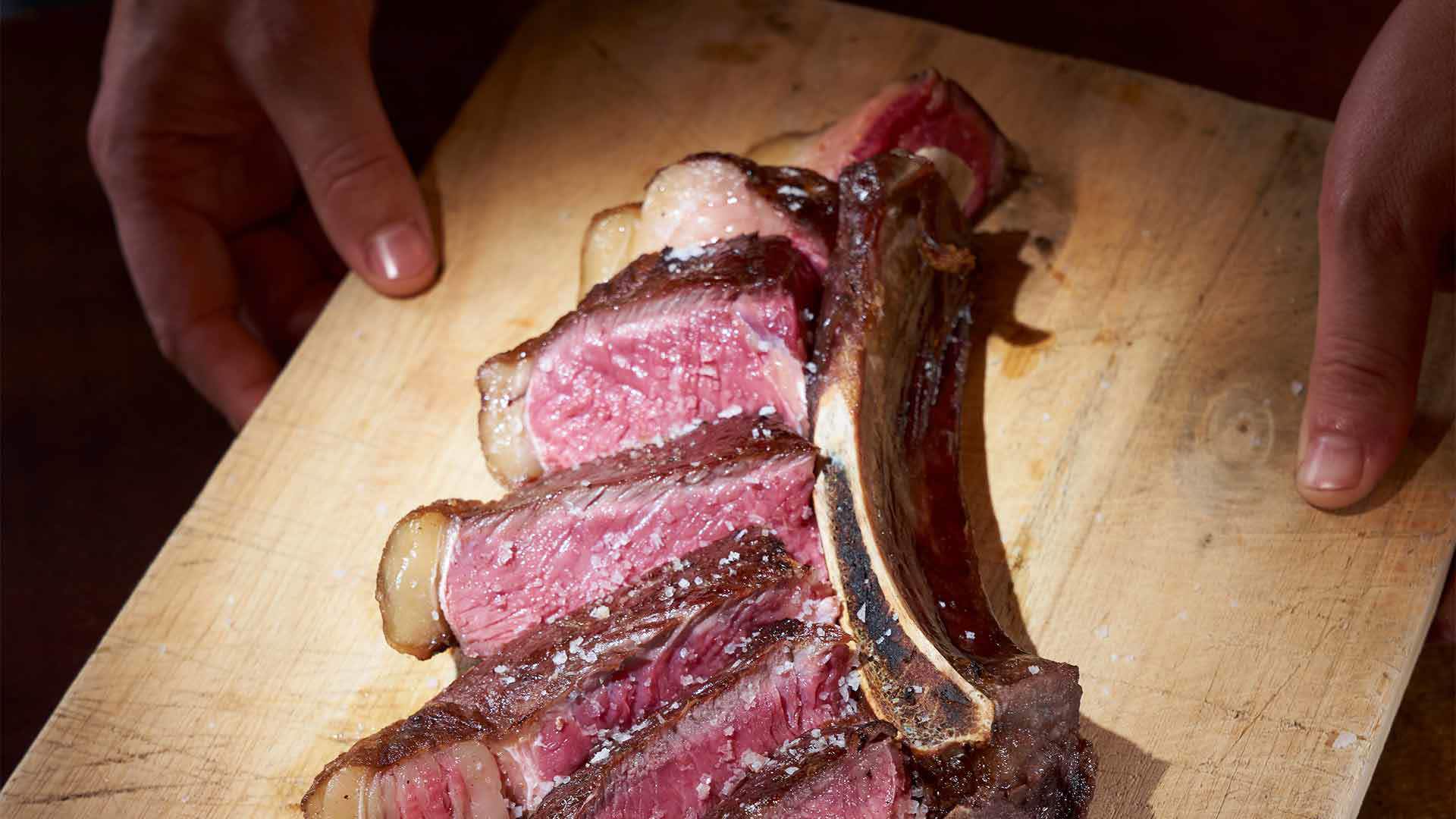 Holzbrett mit geschnittenem Fleisch darauf.