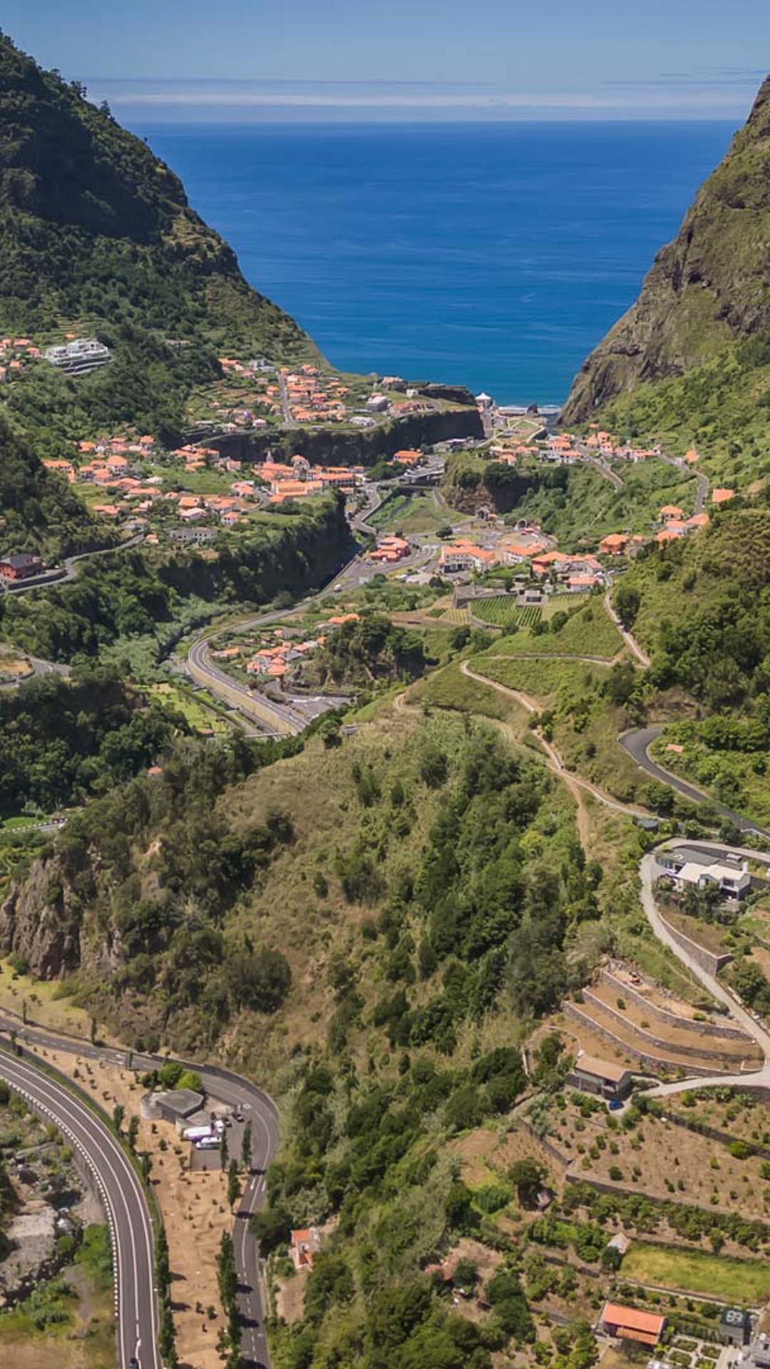 Maisons et routes dans une vallée entourée de nature.