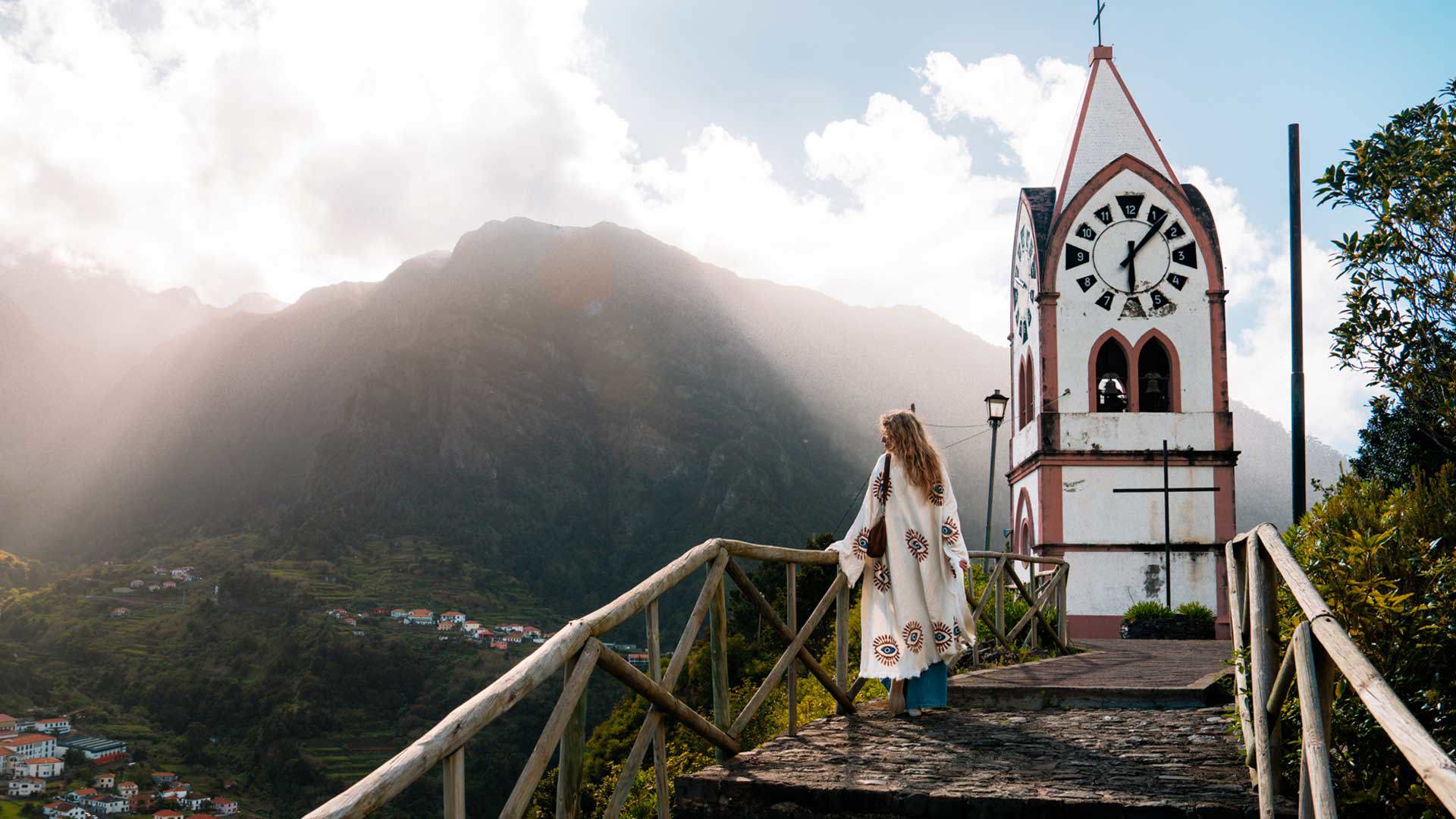 Church surrounded by nature with a woman enjoying the sunny landscape on Madeira Island.