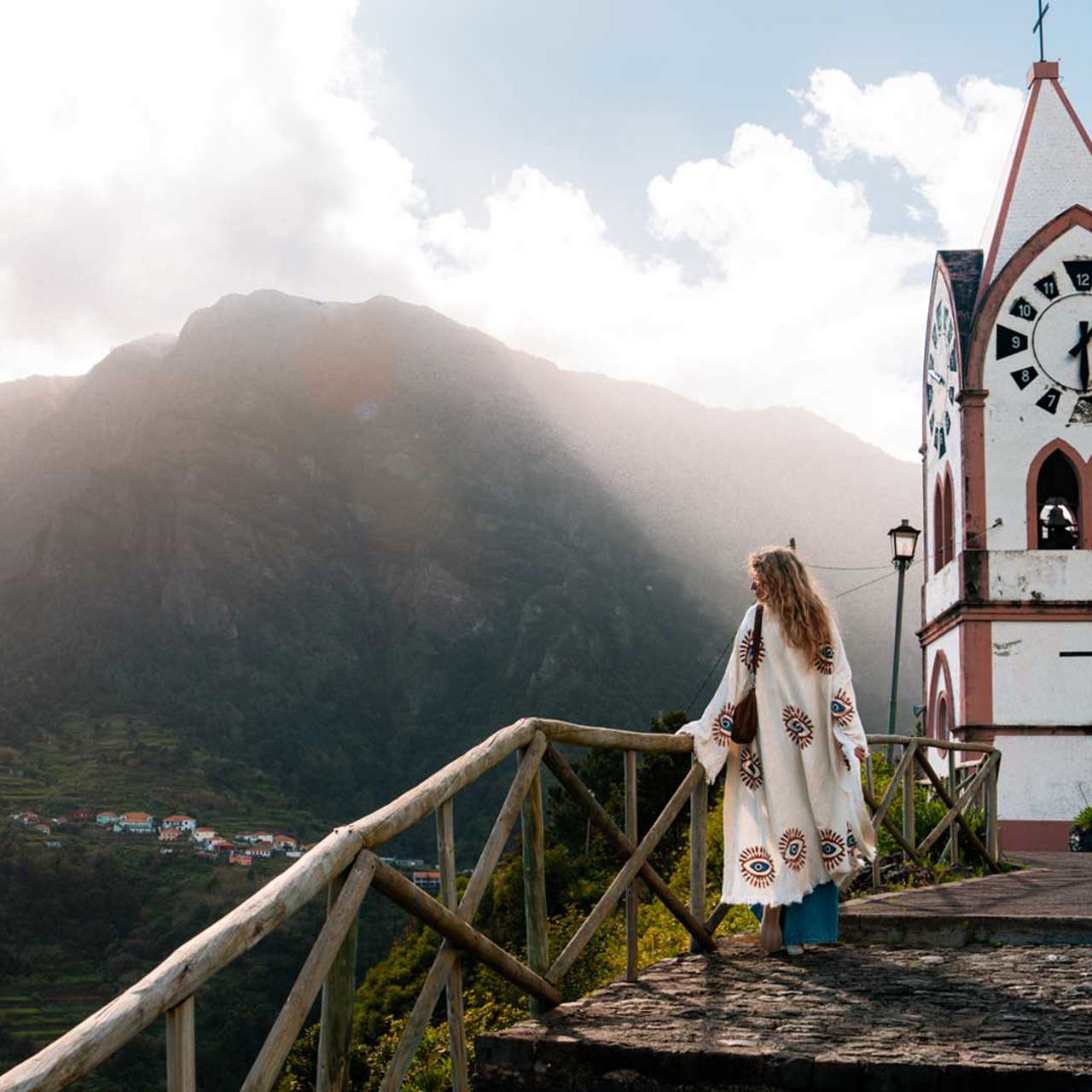 Iglesia rodeada de naturaleza con una mujer disfrutando del paisaje soleado, en la isla de Madeira.
