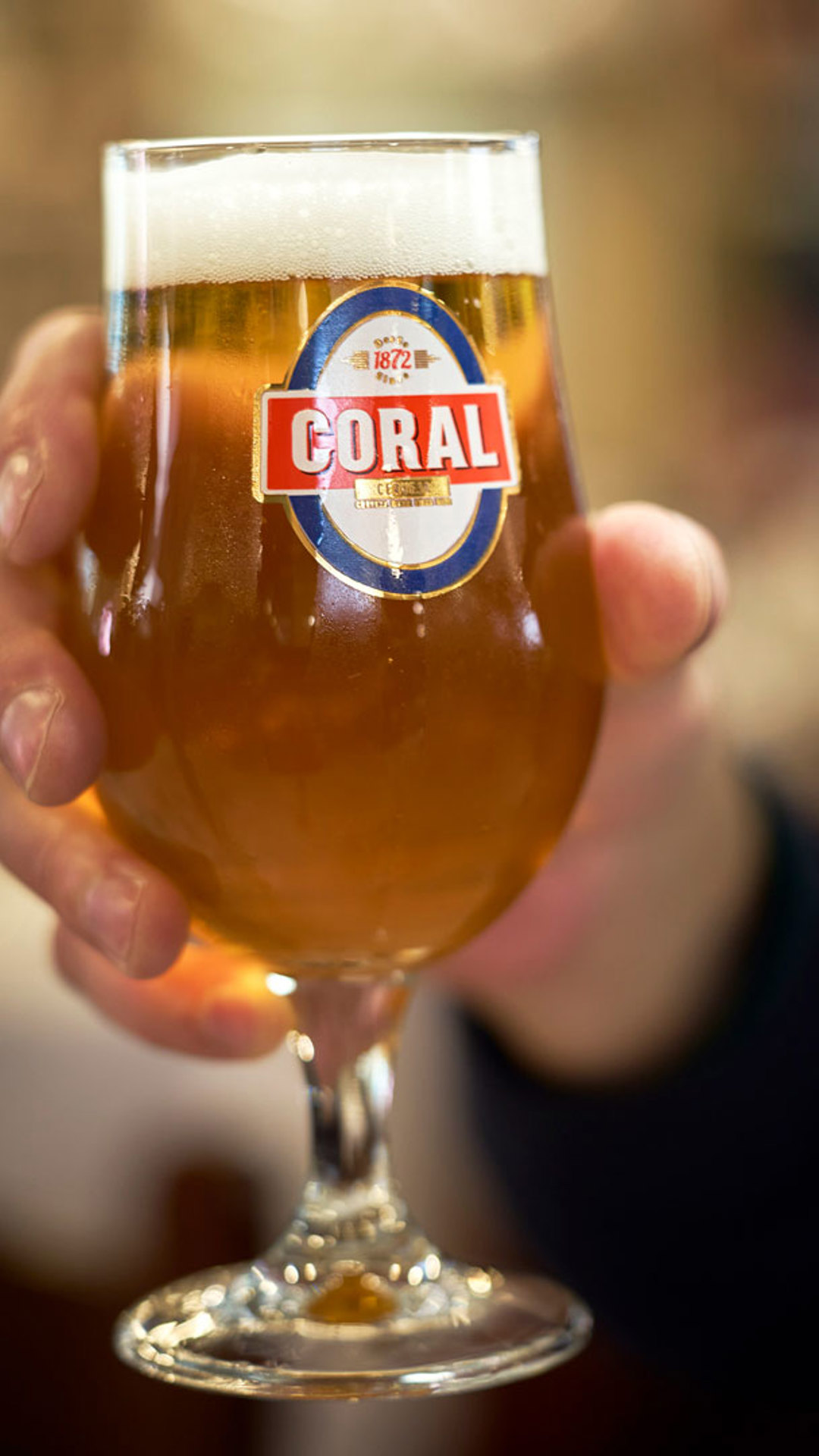 Mano sosteniendo una copa de cerveza Coral en la isla de Madeira.