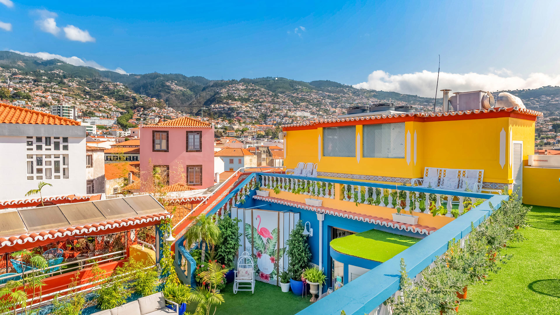 Terrace with blue balcony and yellow building facing the mountain.