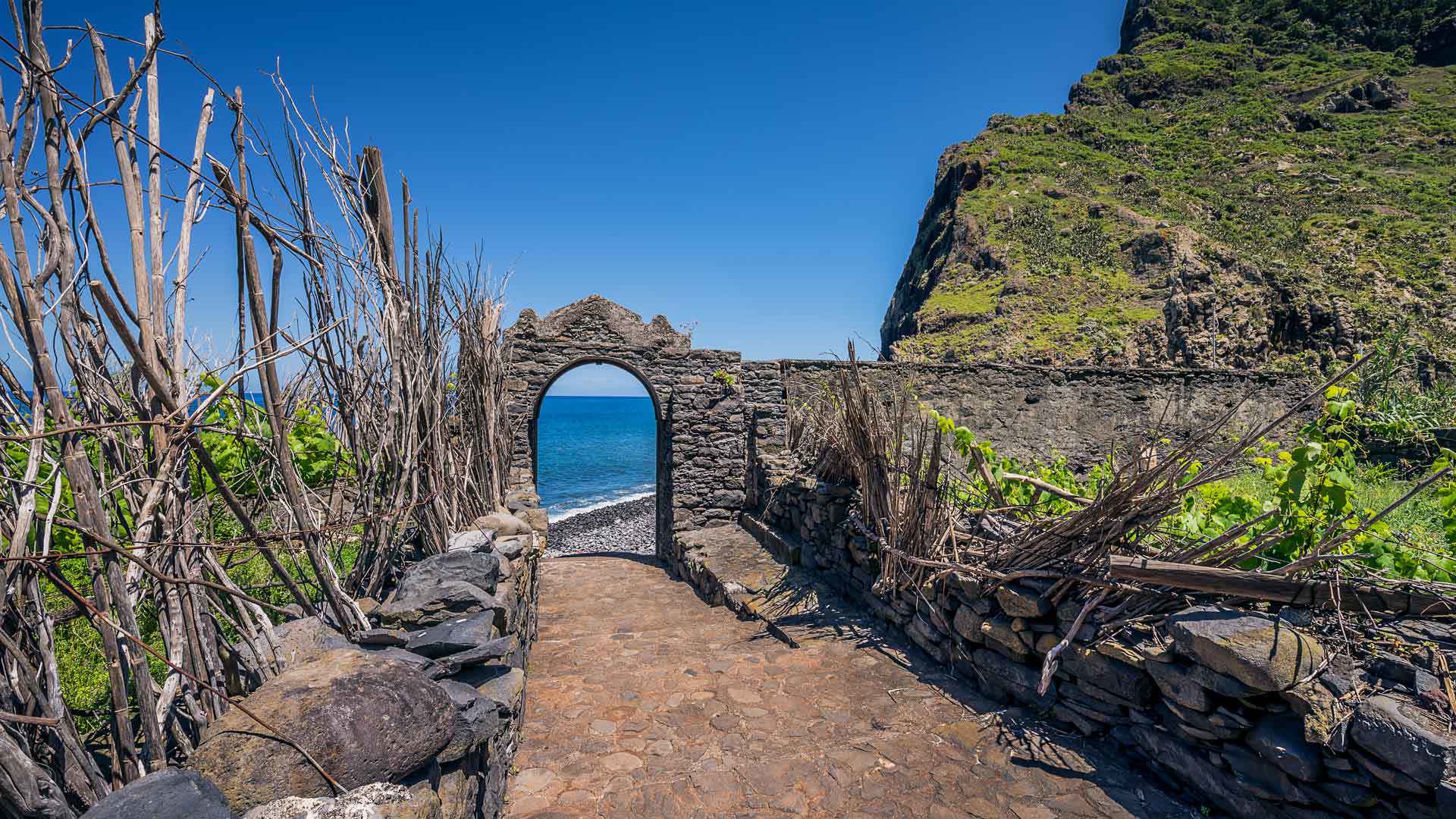 Escadas junto a arco de pedra com vista para o mar na Madeira.