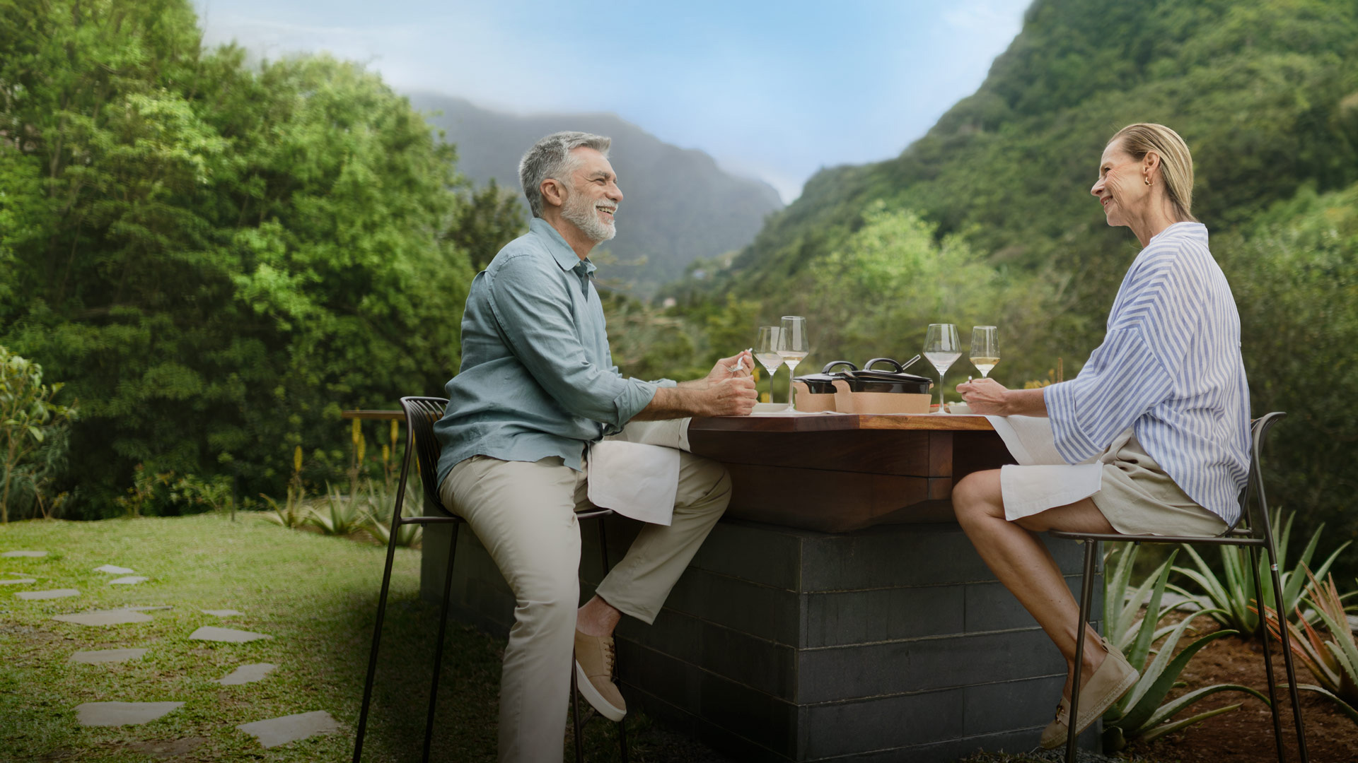 um casal numa mesa num jardim a desfrutar de um copo de vinho