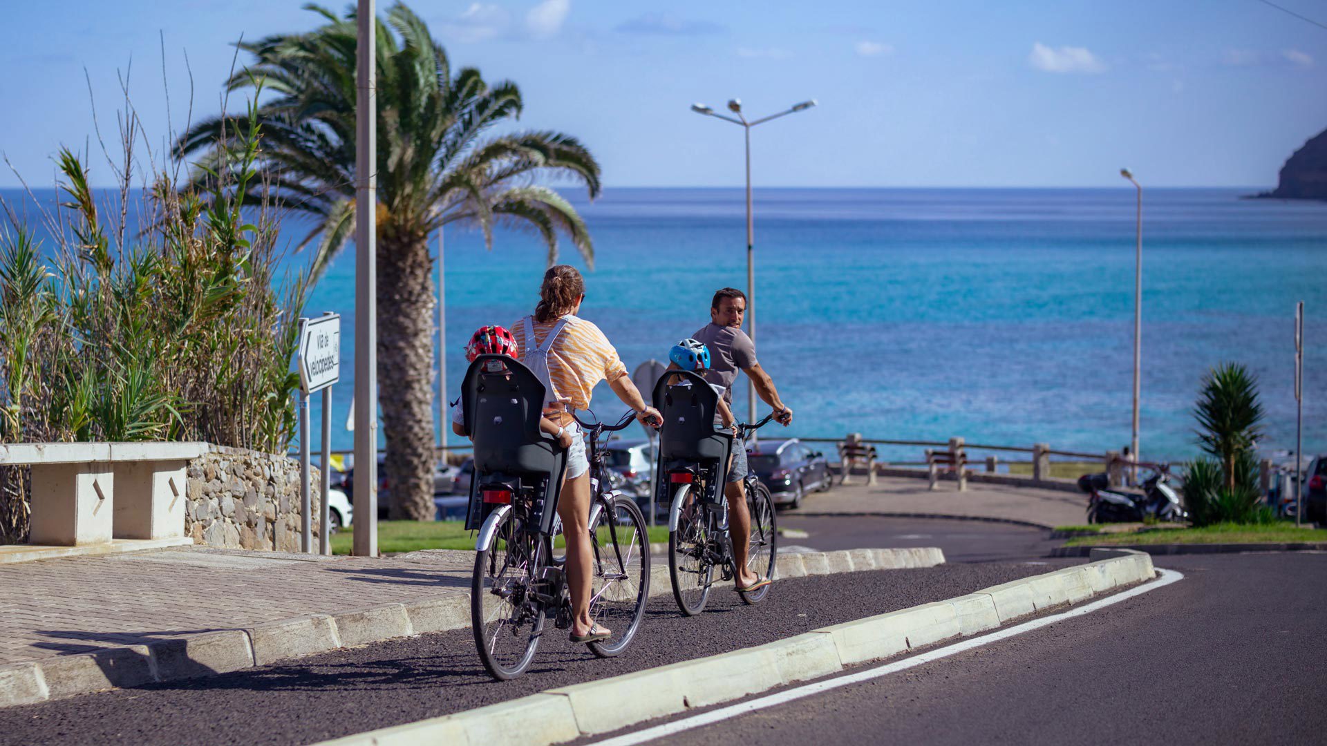Familie fährt Fahrrad auf Porto Santo, Eltern treten in die Pedale und Kinder folgen hinten.