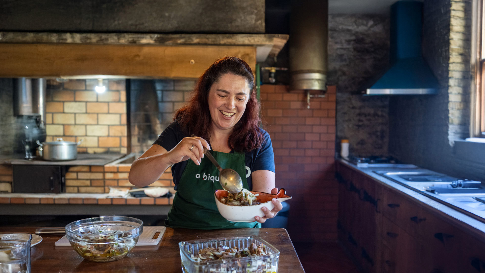 Frau mit Schürze hält eine Schüssel mit Essen.