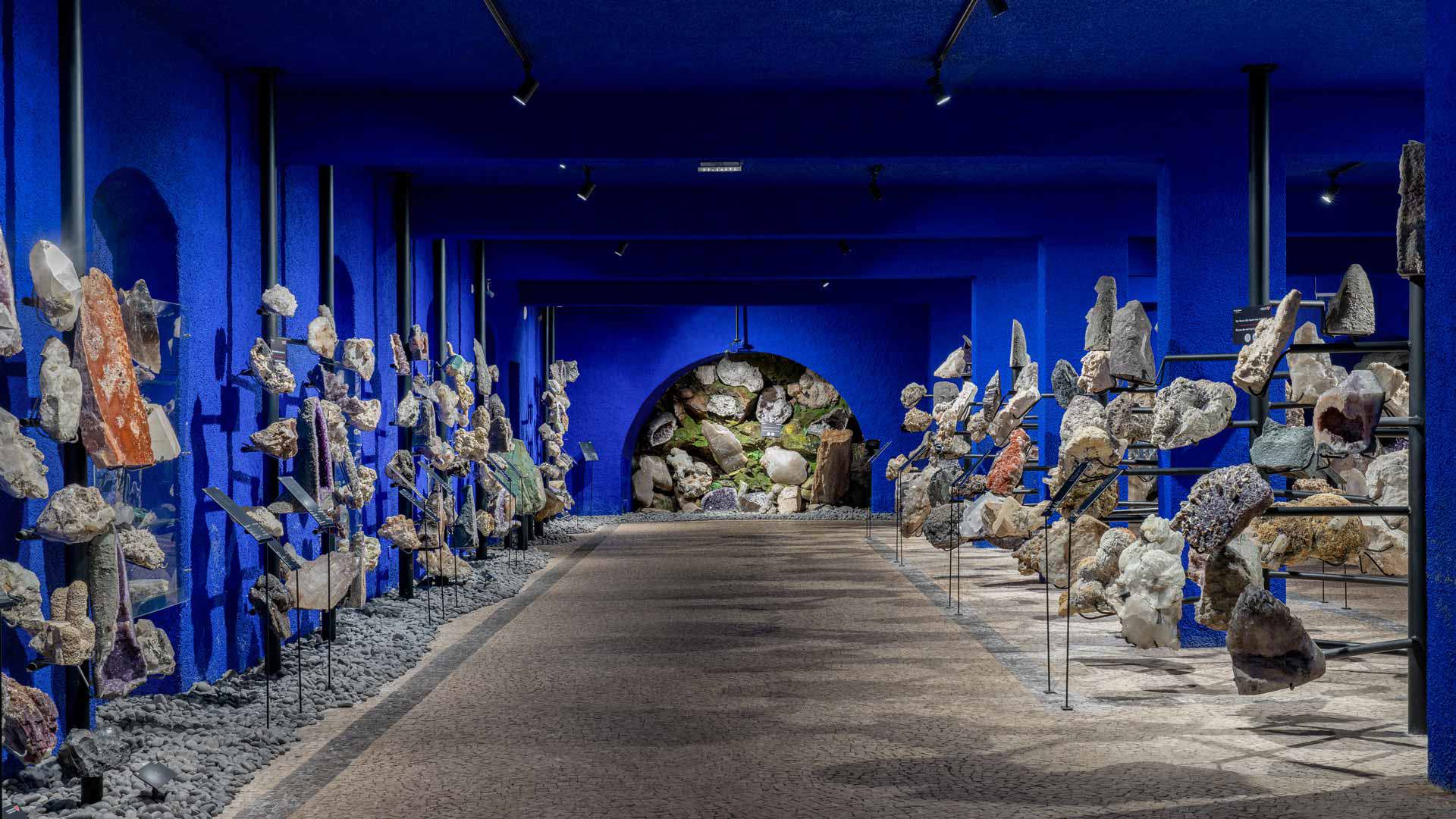 Exhibition of precious stones and minerals at Monte Palace Museum in a blue room.