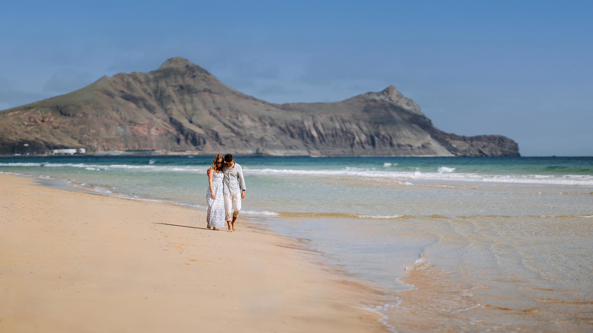 Couple walking by the sea on Porto Santo beach.