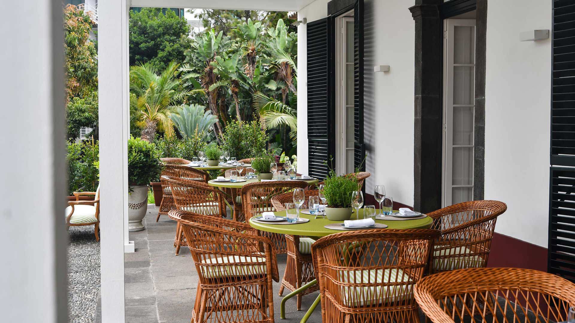 Tables dressées à l’extérieur d’un restaurant, entourées de plantes.