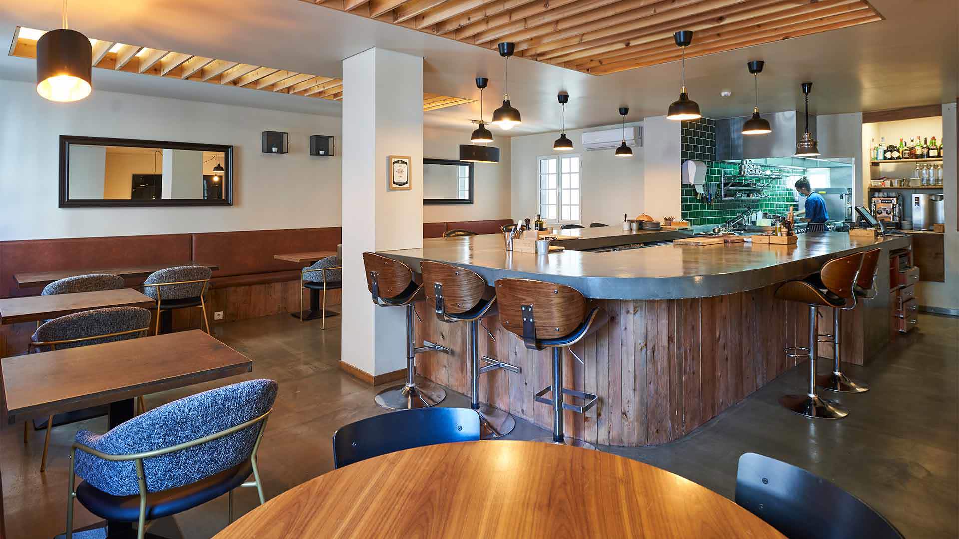 Theke mit Stühlen, Tischen und Deckenbeleuchtung.