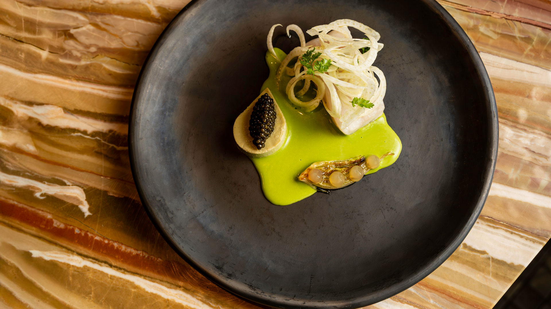 Gourmetgericht mit grüner Sauce angerichtet im Stil der zeitgenössischen Küche.