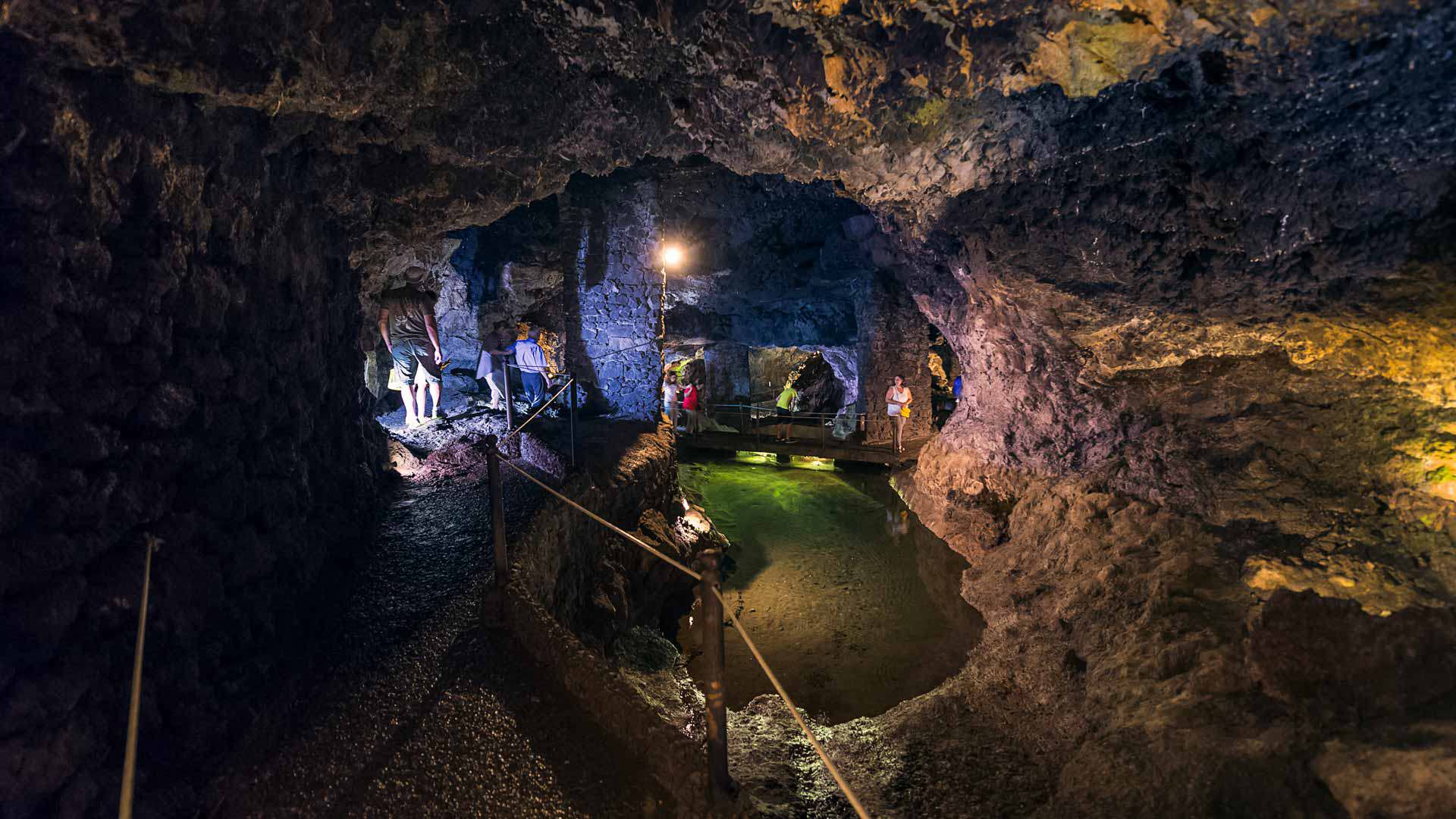 Grotte éclairée avec formations rocheuses visibles.