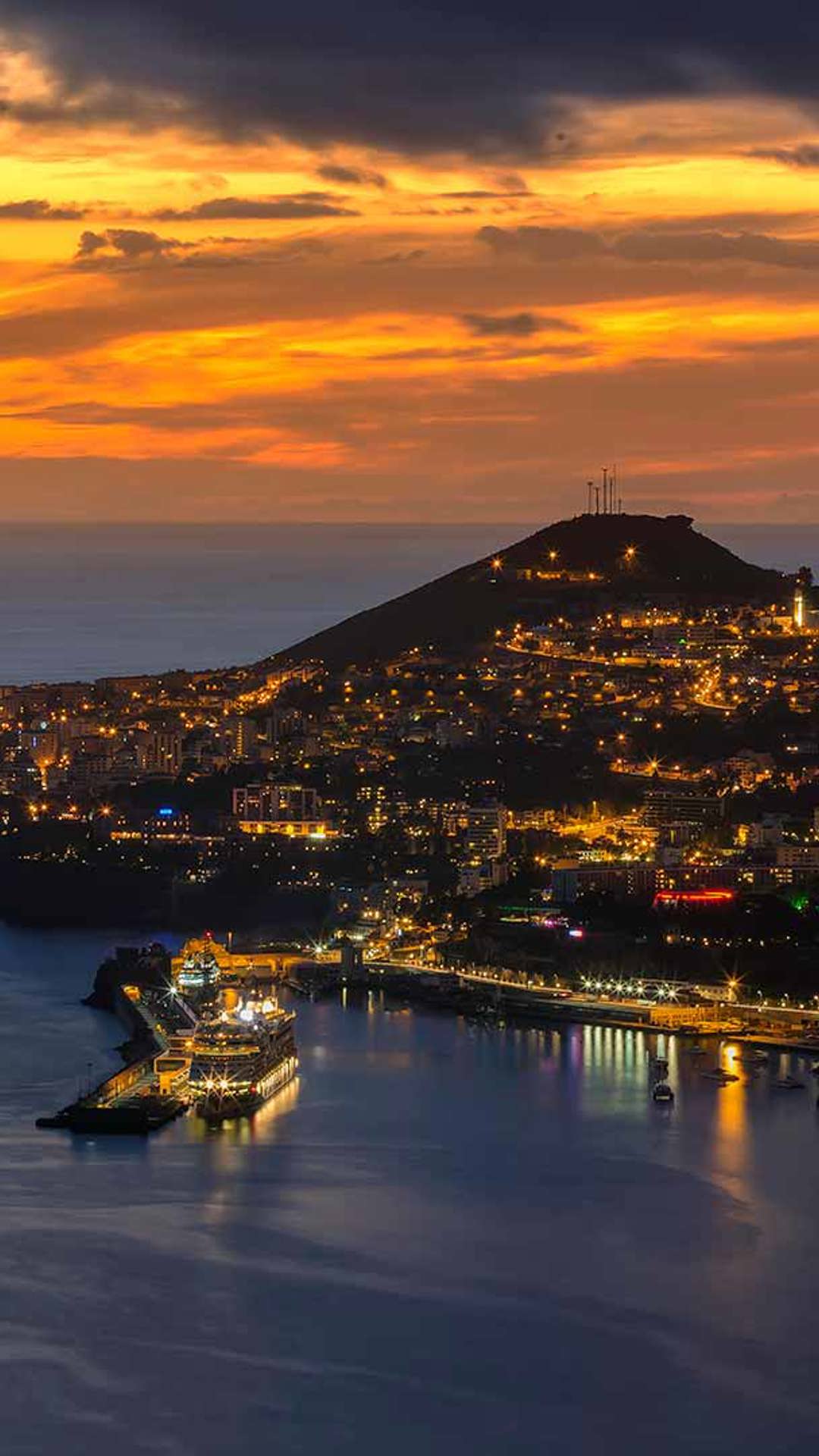 Atardecer sobre el mar con luces de la costa en Madeira.