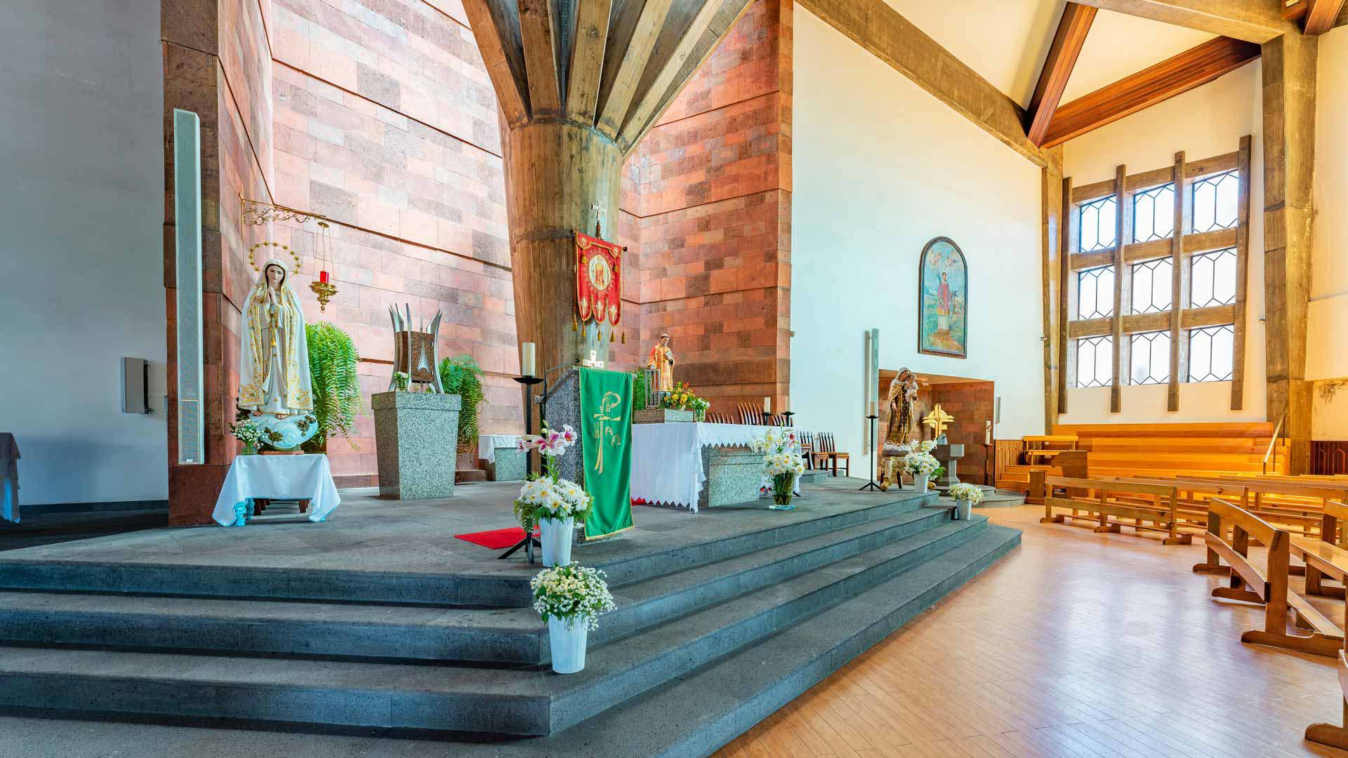 Intérieur d’église avec bancs en bois, autel, piliers et vitraux colorés.