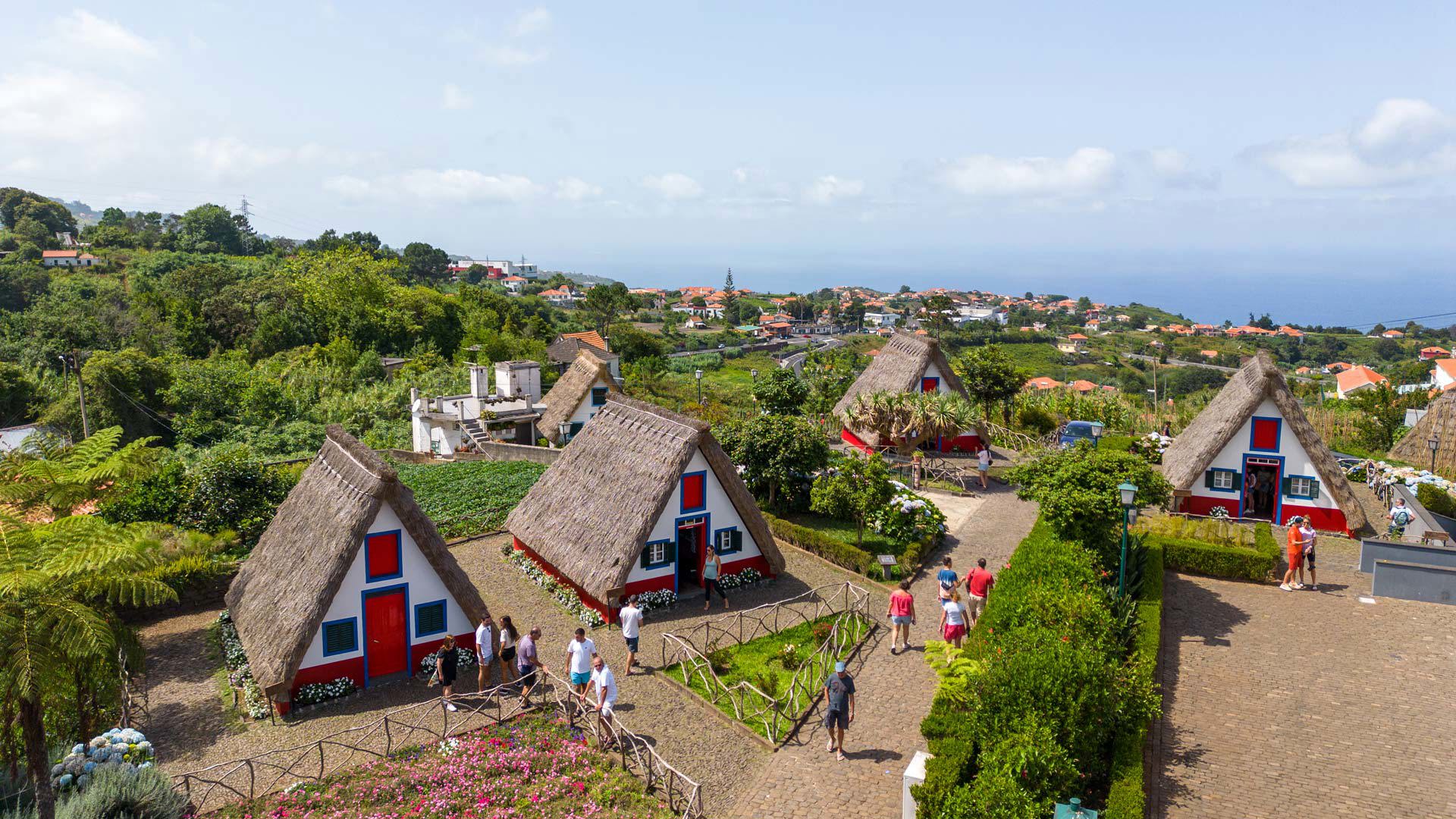 Triangular houses with gardens and people in Madeira.