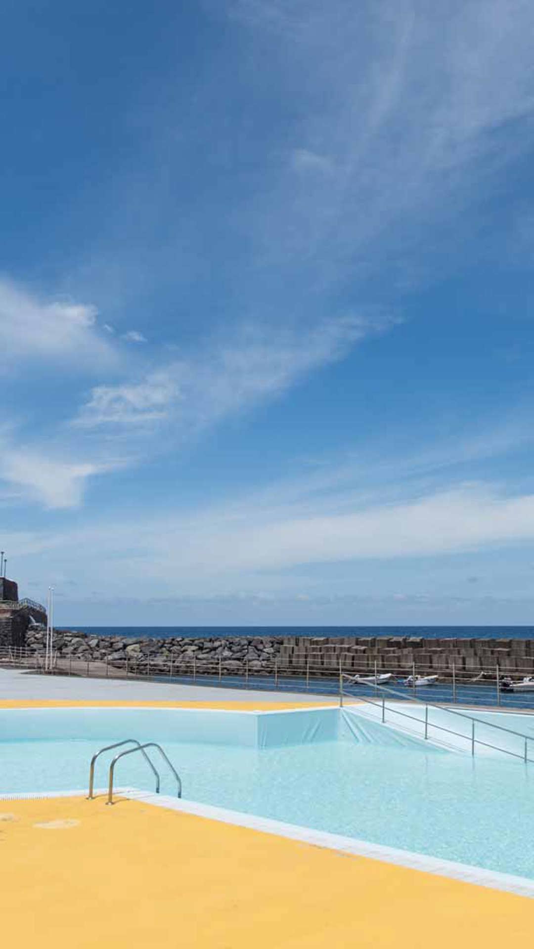 Piscine avec ciel bleu et maisons en arrière-plan à Madère.