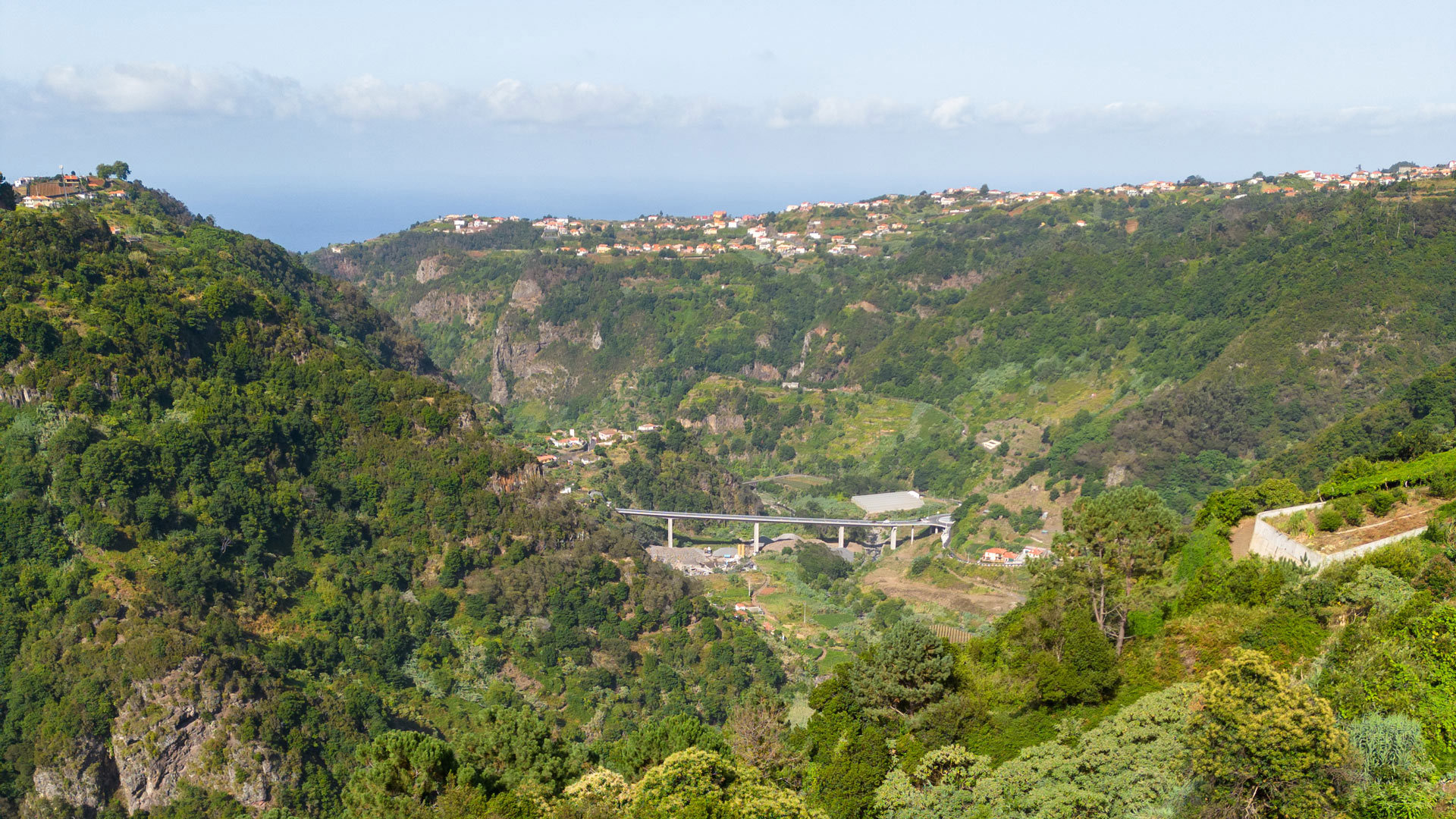 Berge und grünes Tal mit Häusern in der Ferne auf Madeira.