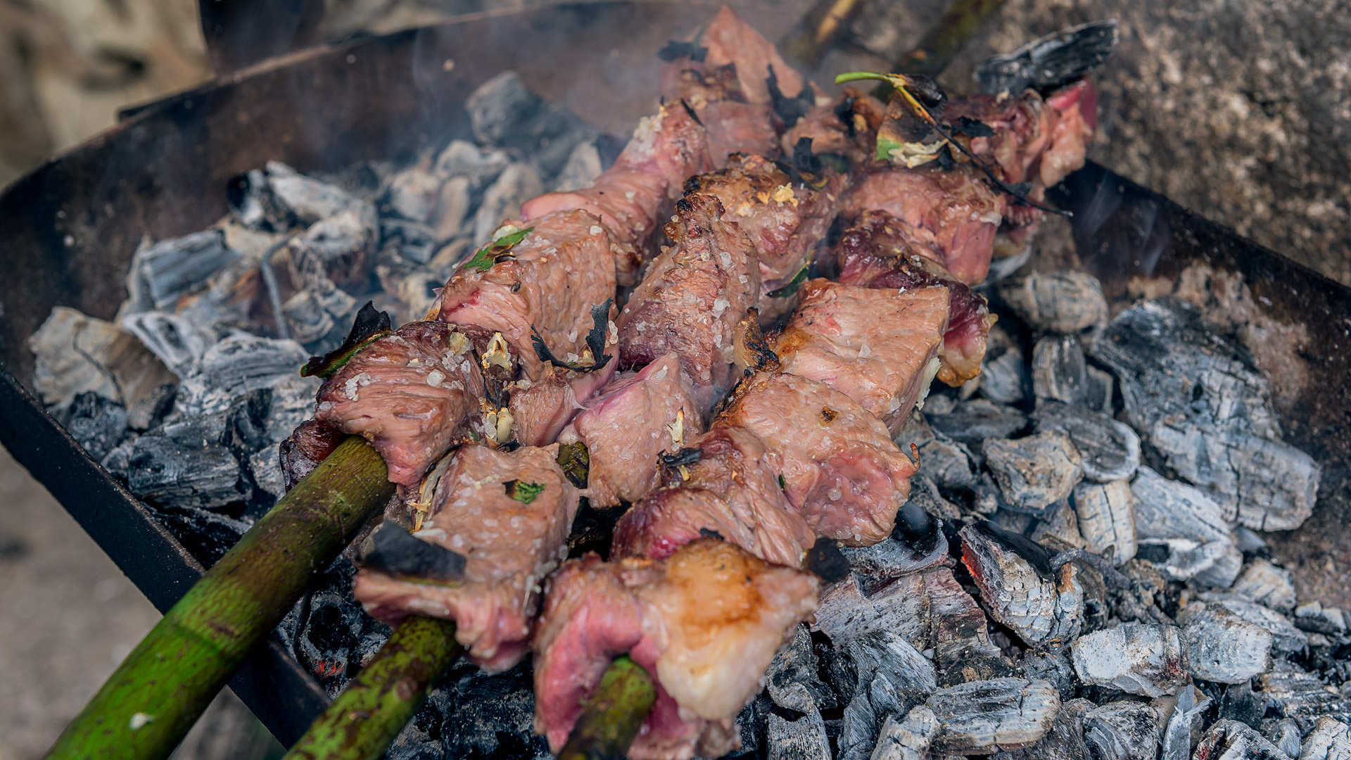 Drei Lorbeer-Spieße mit Espetada, die über einem Grill zubereitet werden.