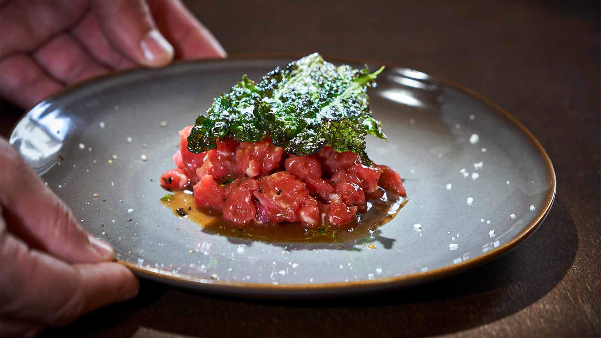 Teller mit Rindertatar und Gemüse darauf.